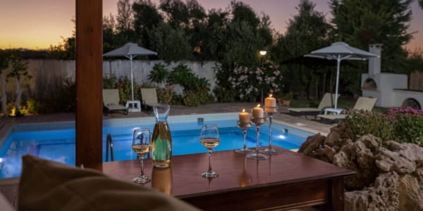 a table with wine glasses and bottles by a pool