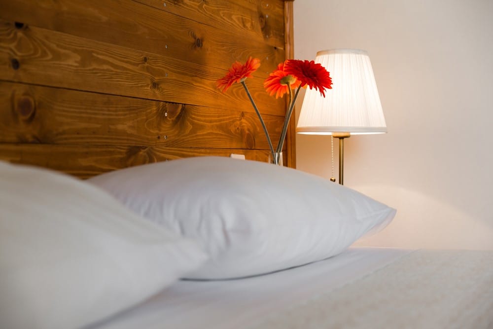 a vase of red flowers on a bed