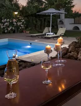 a table with glasses and a candle next to a pool