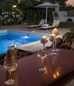 a table with glasses and a candle next to a pool