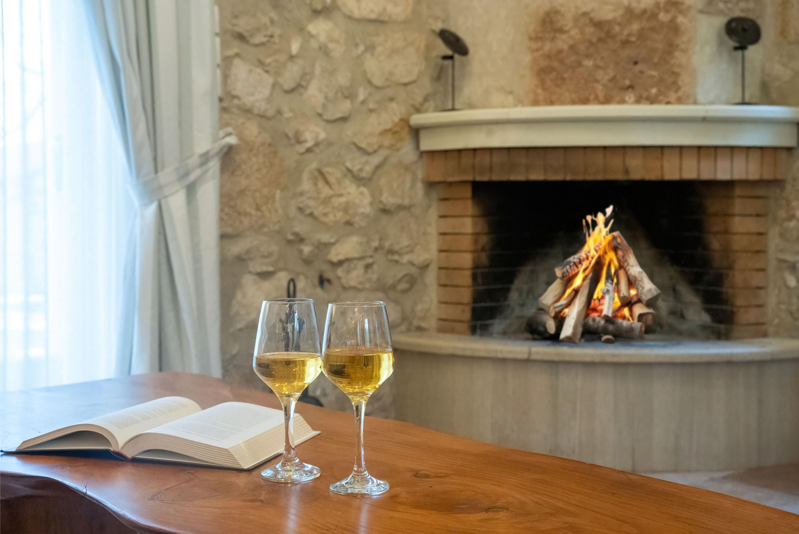 a couple of glasses of wine next to a fireplace