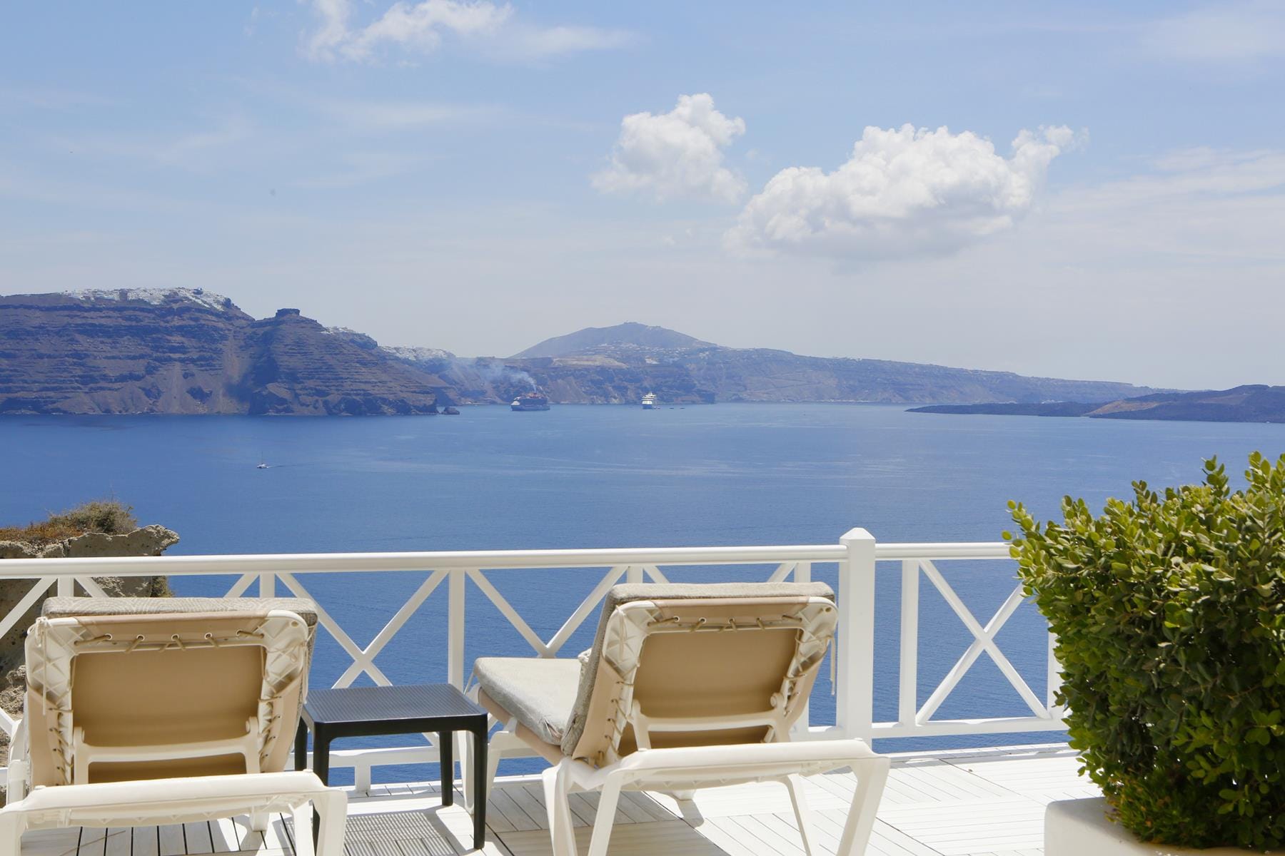 a deck with chairs and a body of water in the background