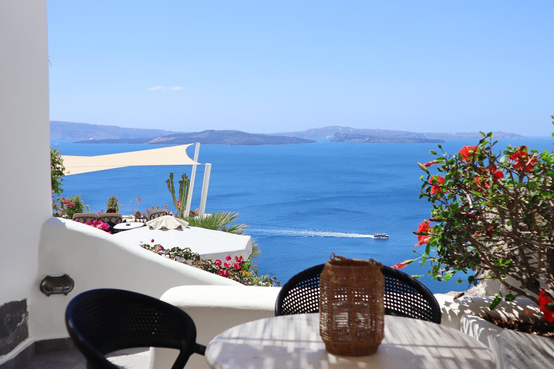 a table with a vase and flowers on it by a body of water