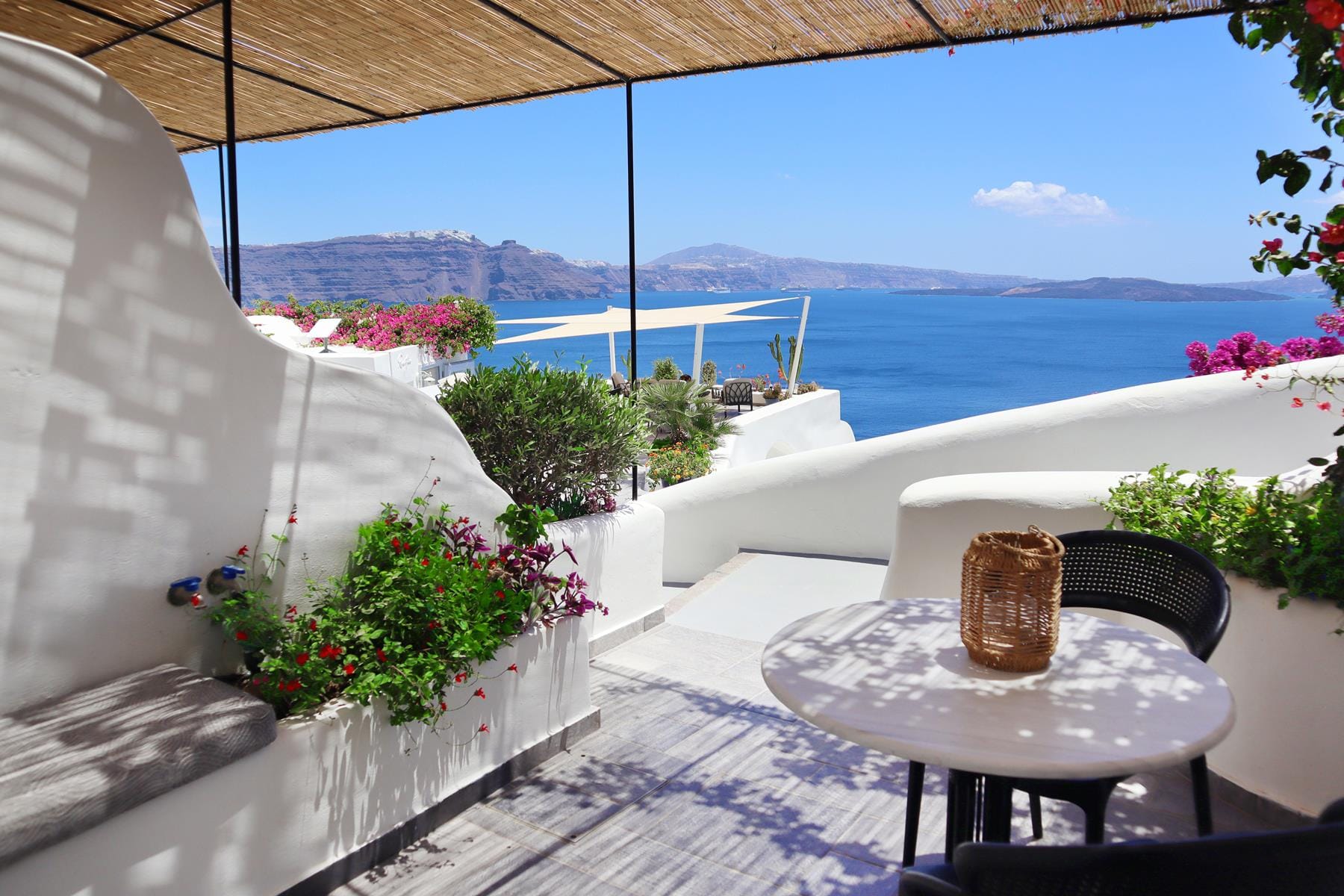 a patio with a table and chairs and a body of water in the background