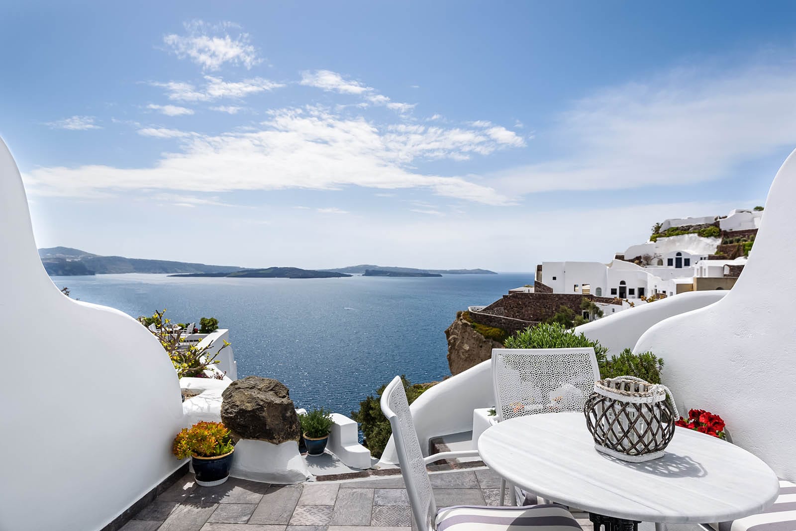 a patio with white chairs and a body of water in the background
