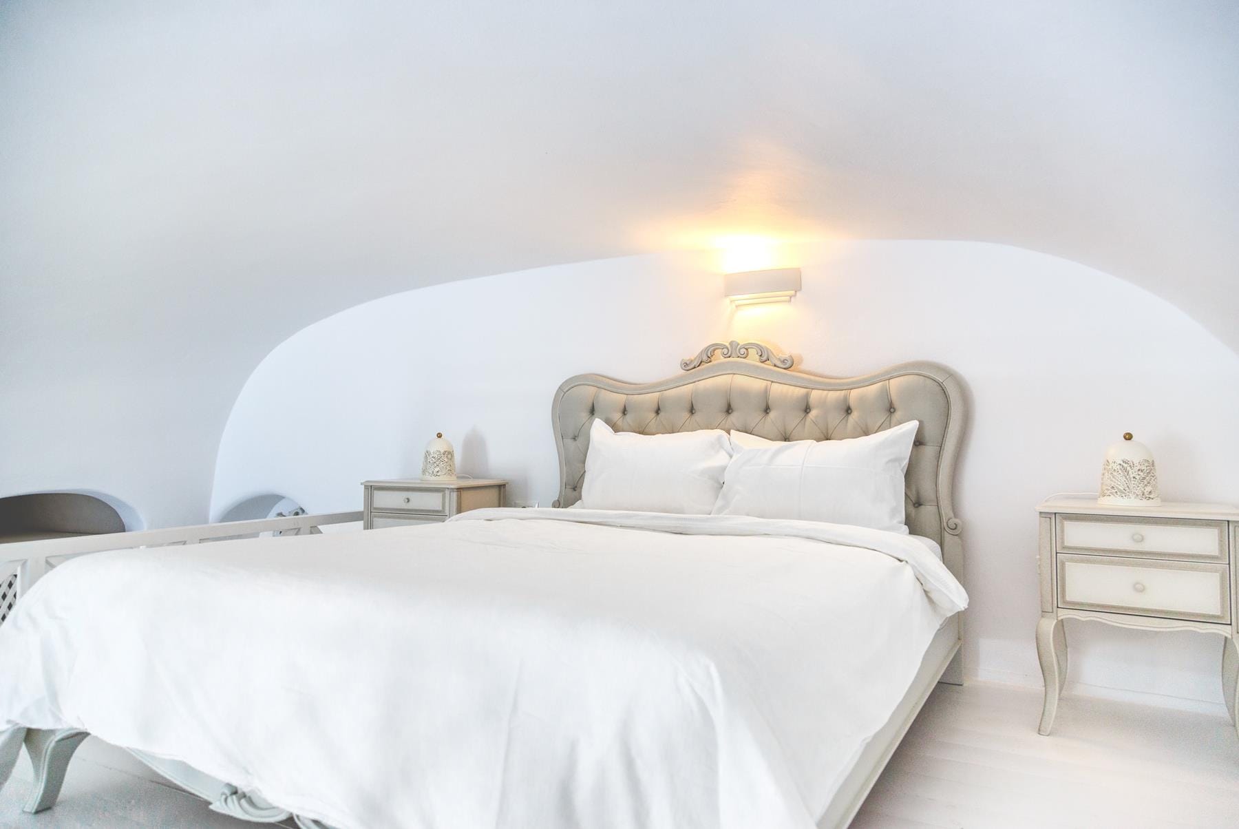 a bed with a white sheet and a white bed with a white headboard and a white wall
