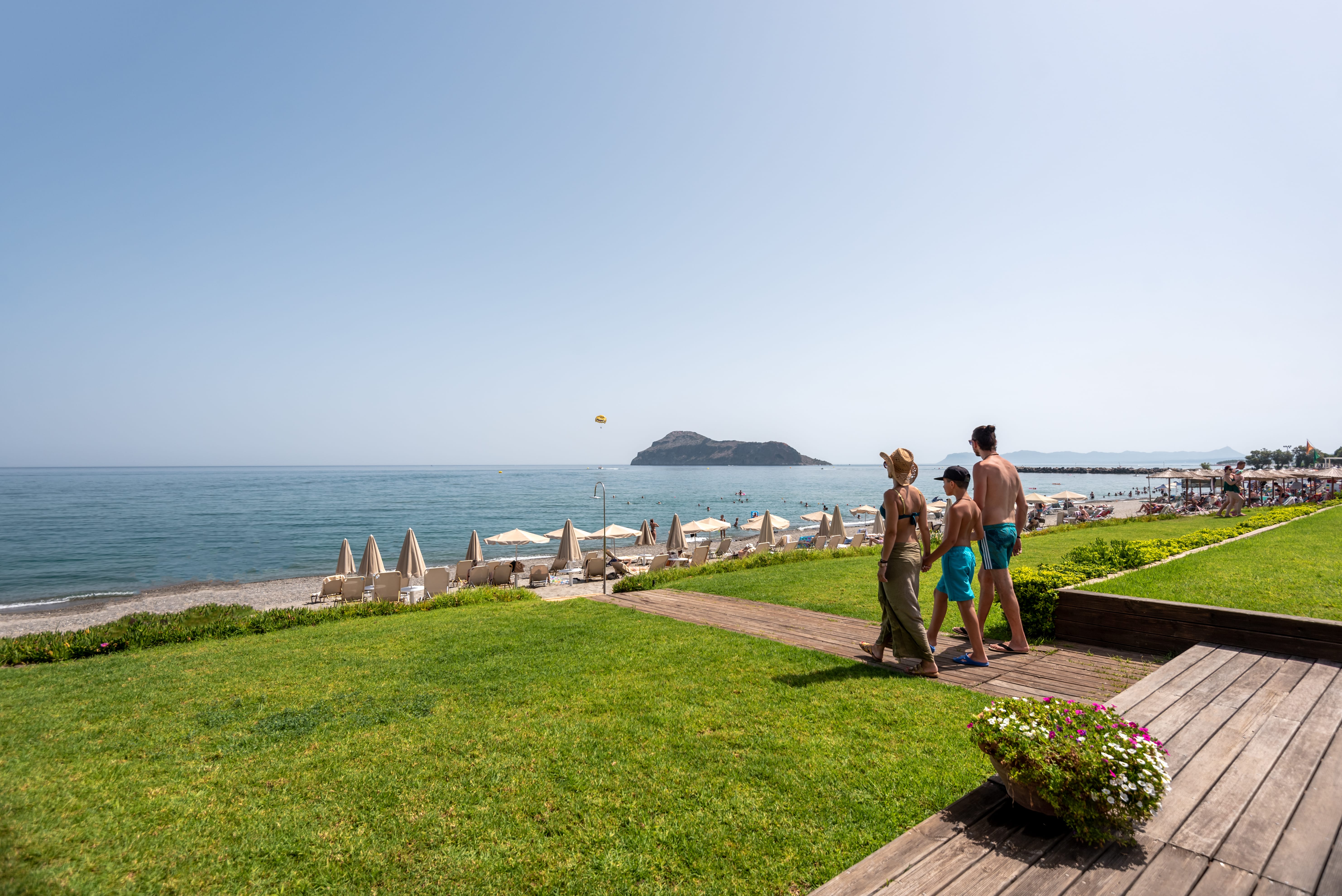 a group of people standing on a path by a beach