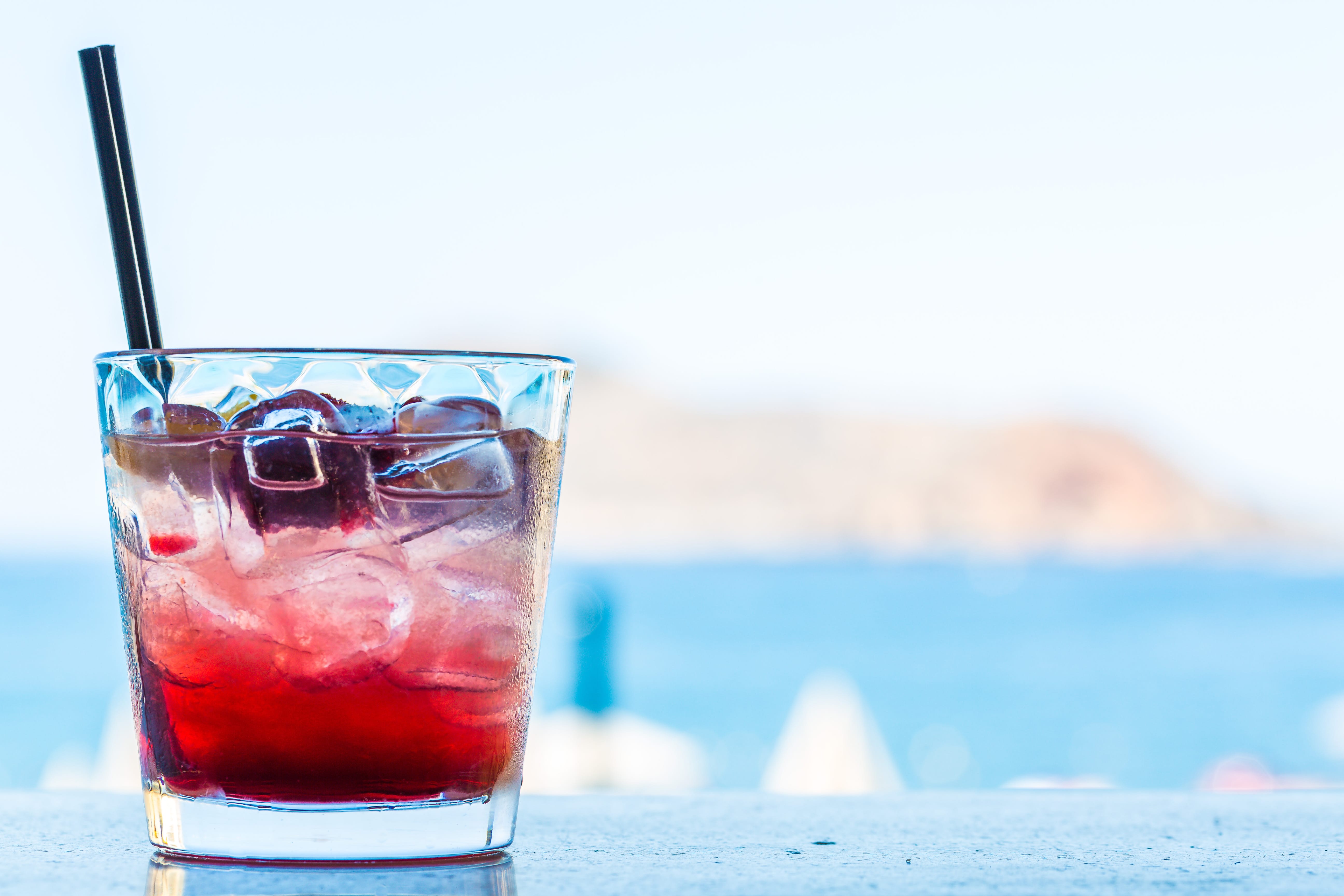 a glass of red liquid with a straw
