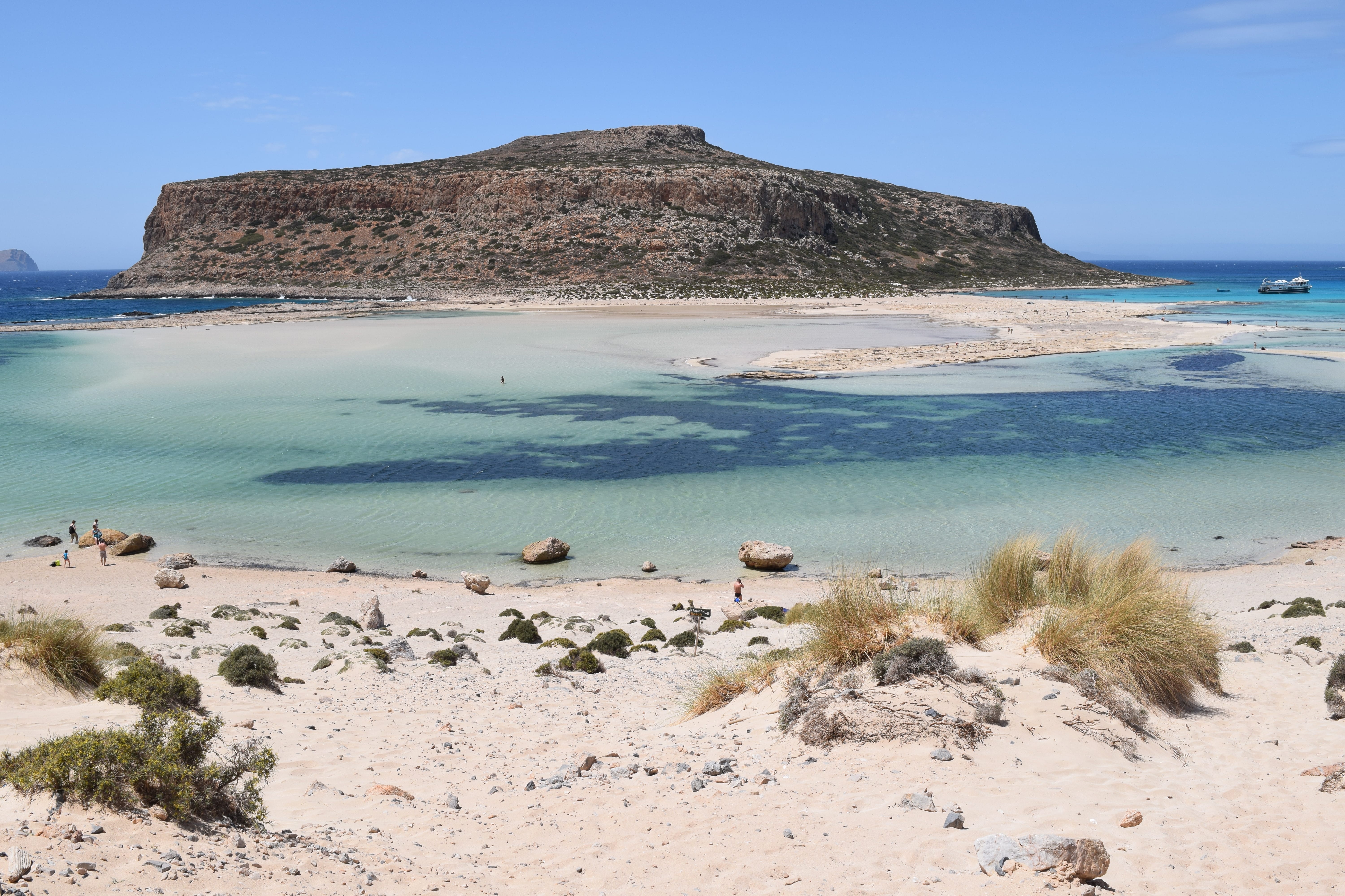 a sandy beach with a hill in the background