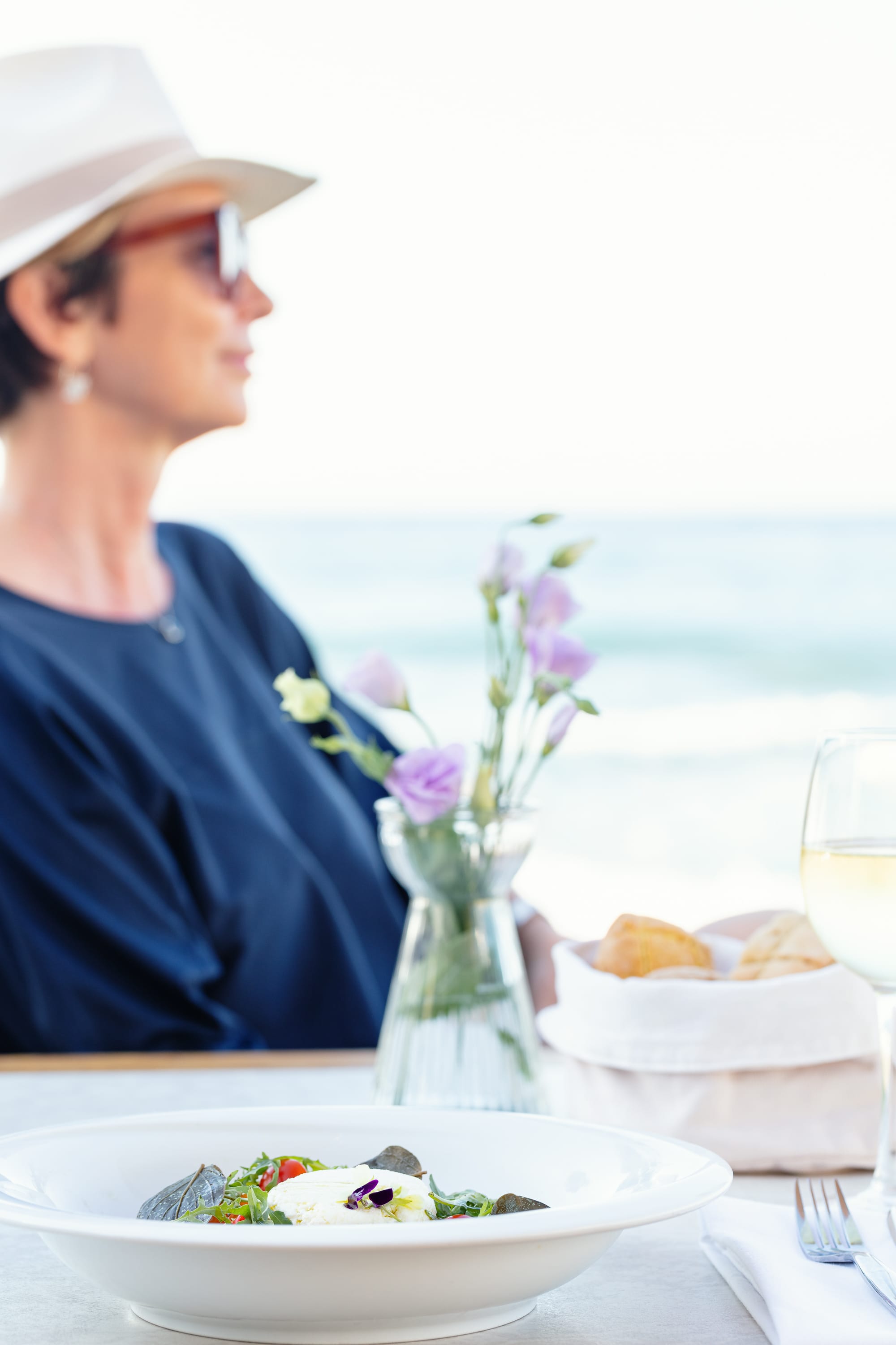 a woman sitting at a table with a vase of flowers