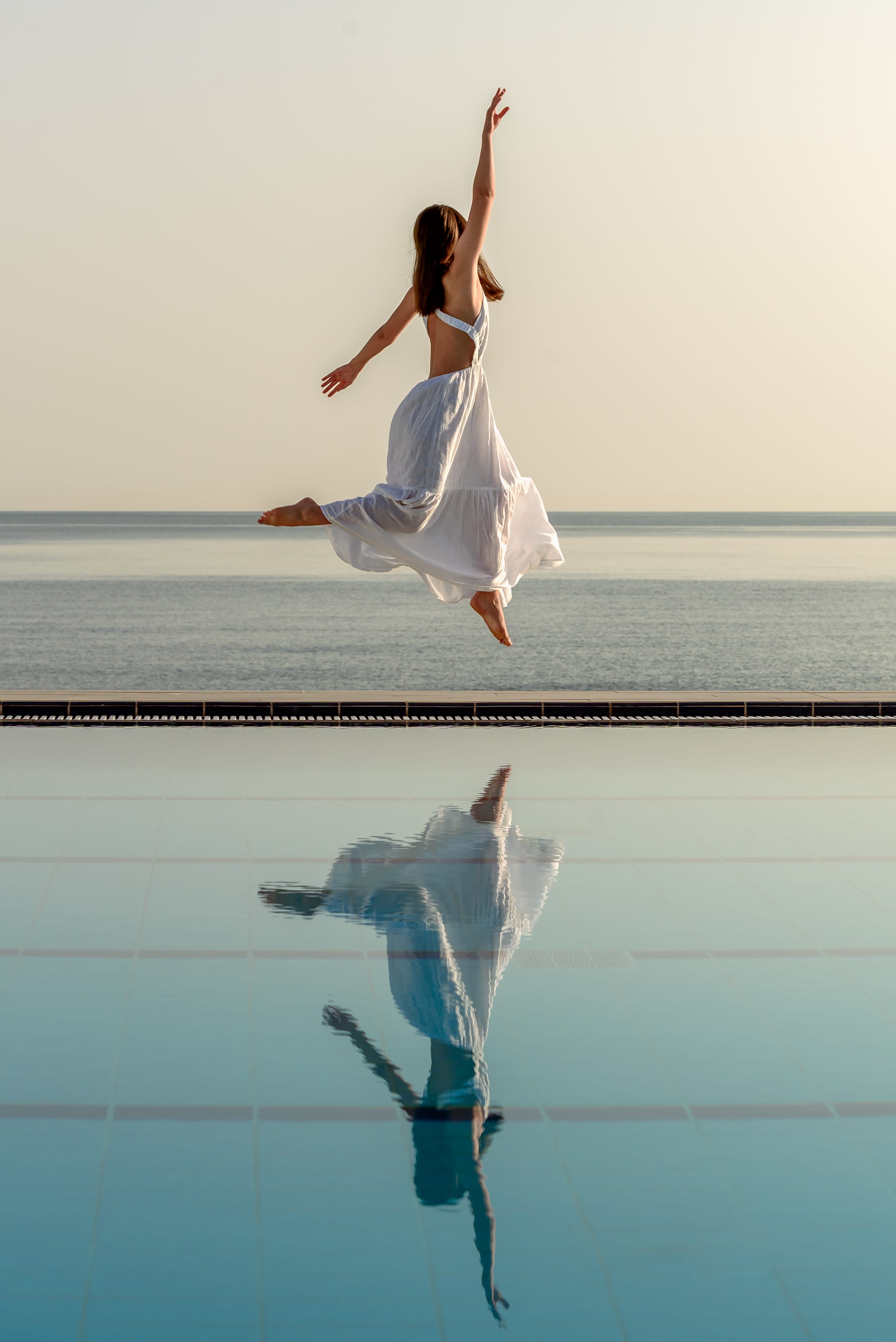 a person jumping in the air with a dolphin in the water