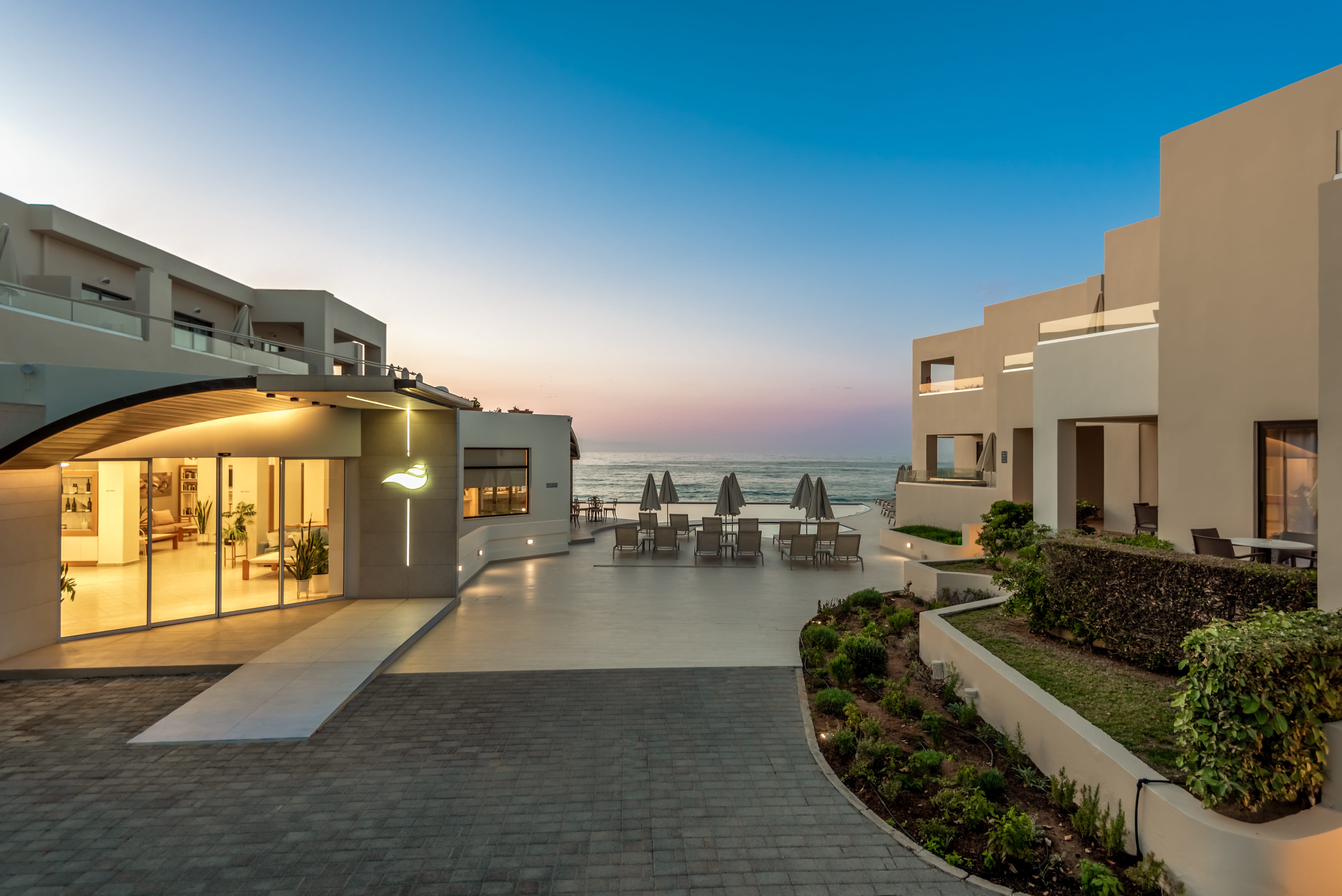 a building with a pool and a beach in the background