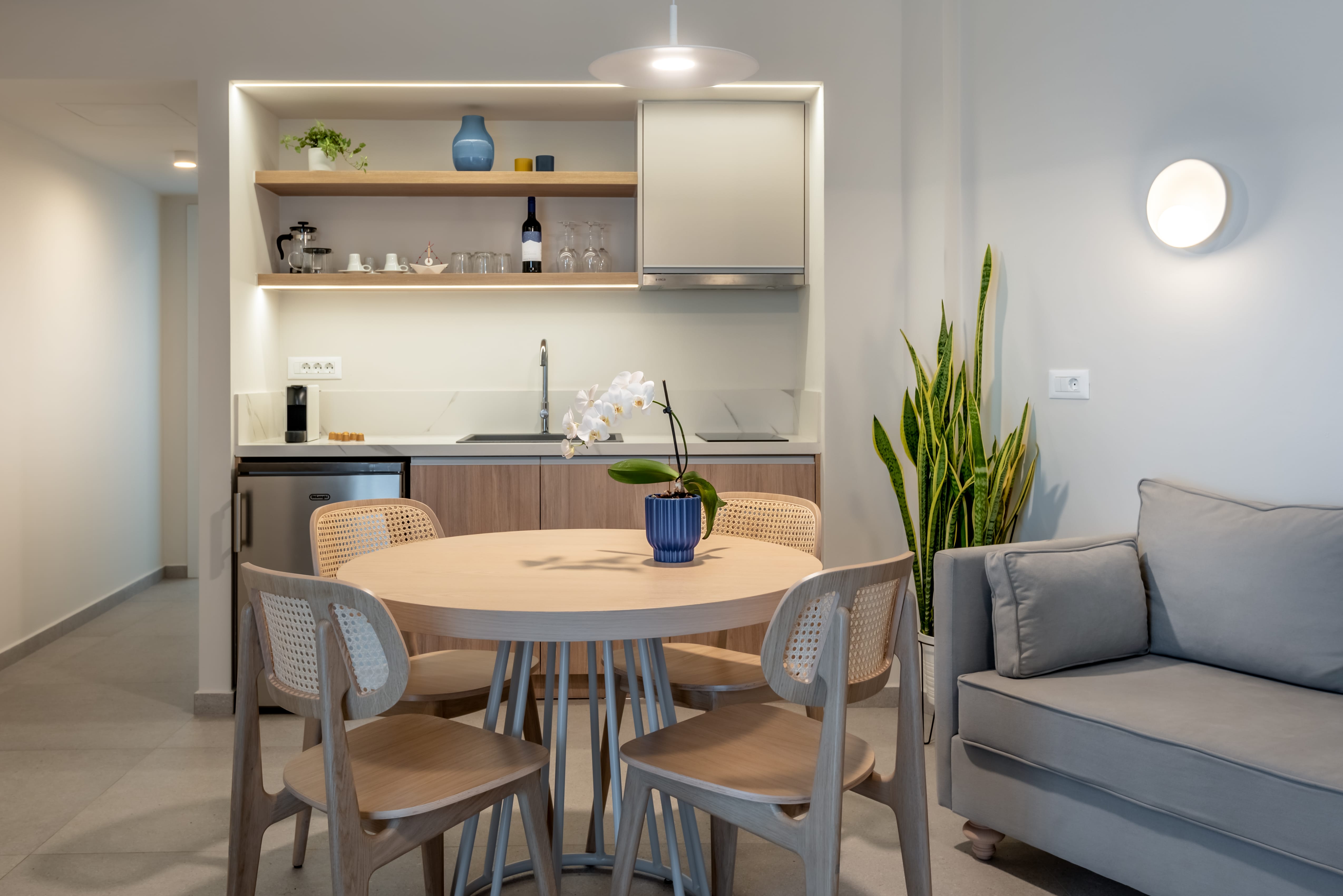 a dining room table with chairs and a shelf with plants on it
