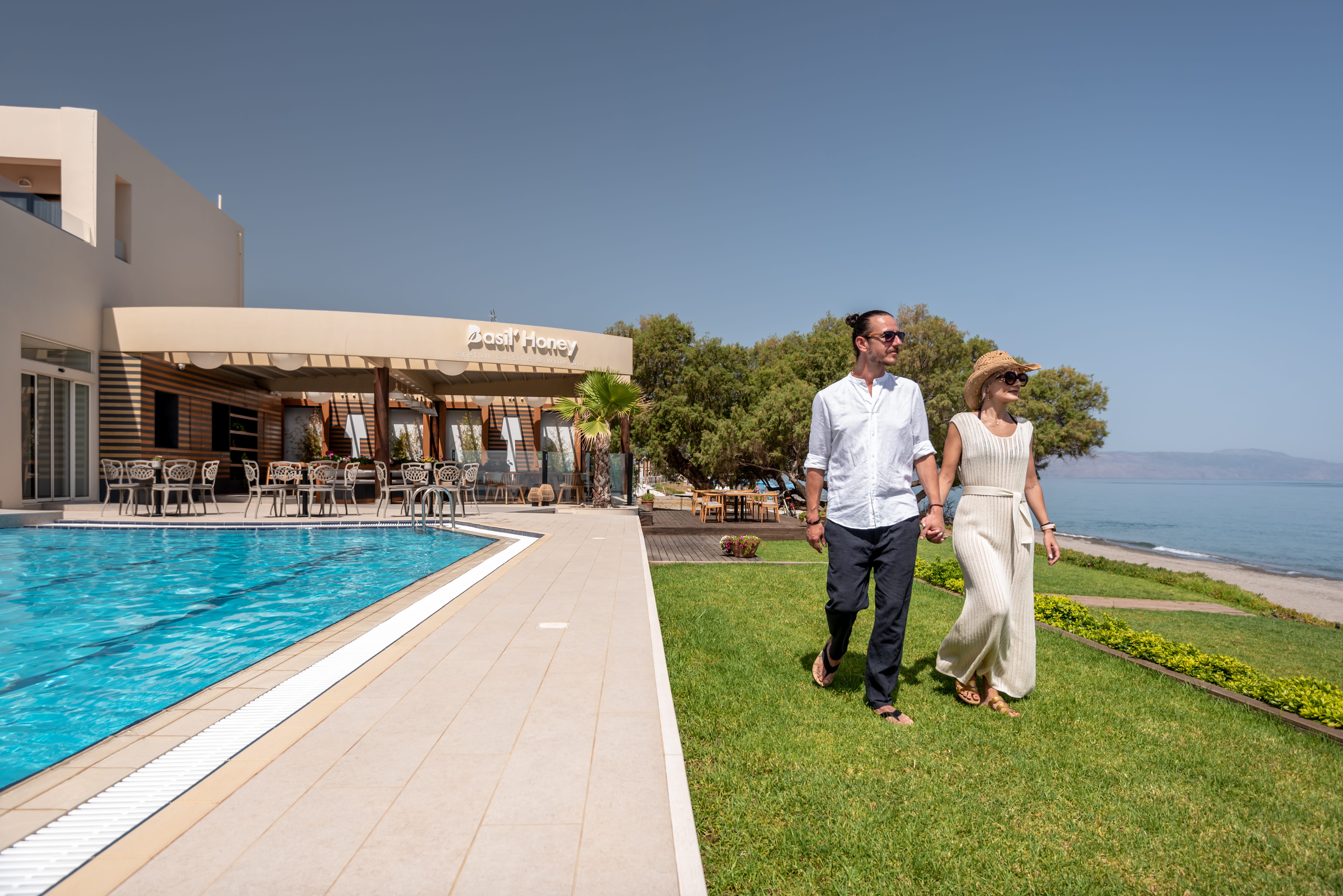 a man and woman walking down a path by a pool