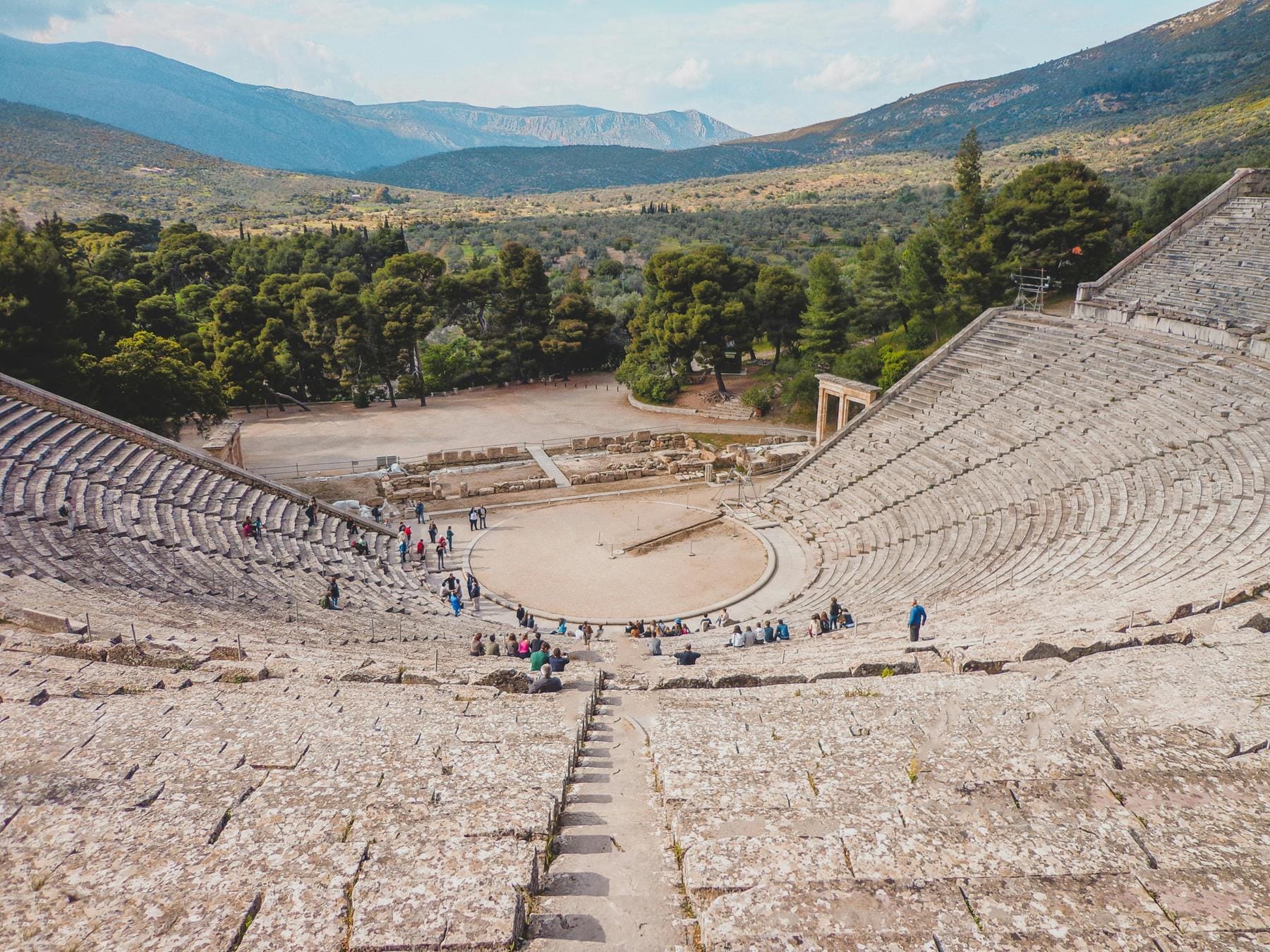 a large group of people at a large circular structure with Epidaurus in the background