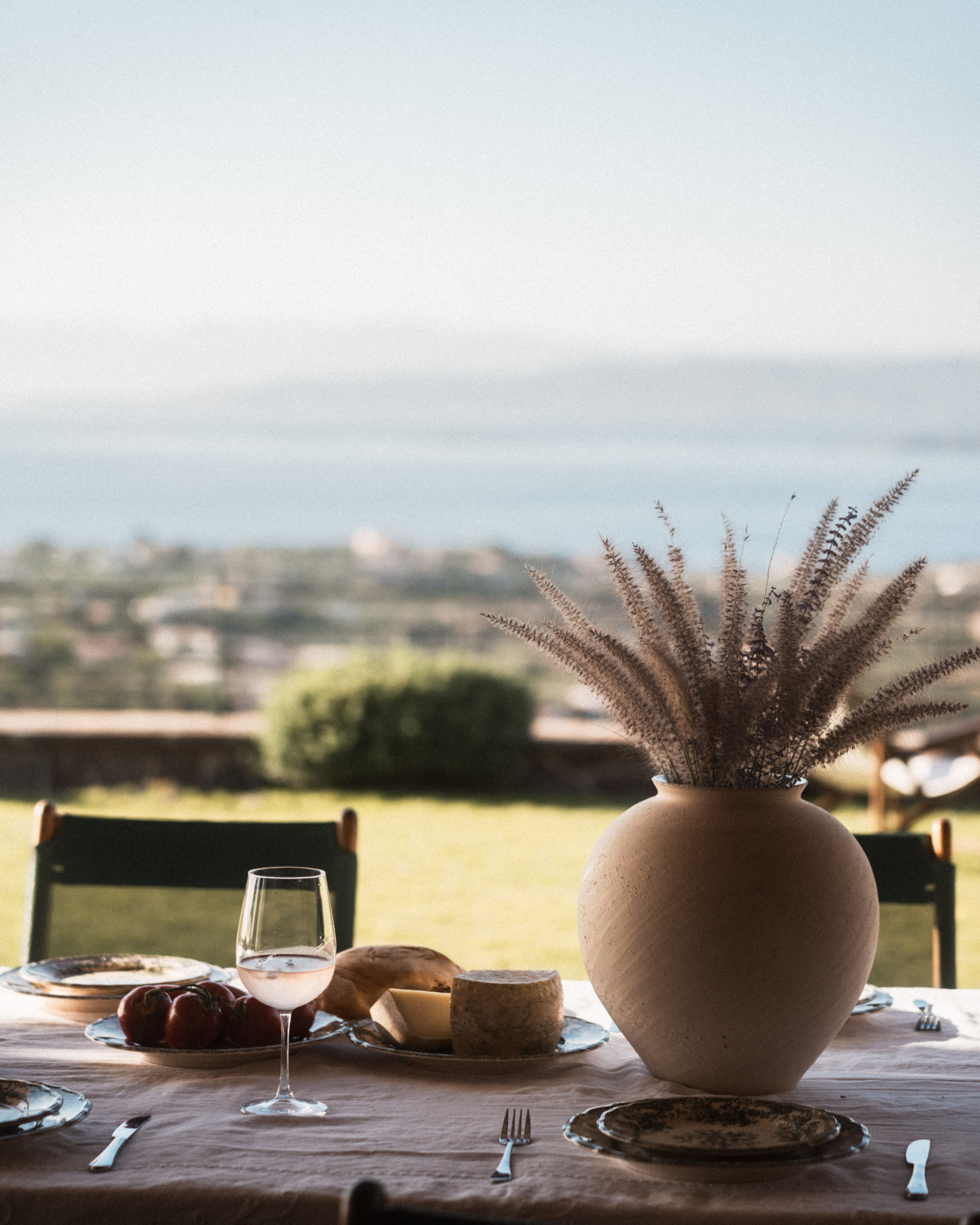 a table with a vase and a glass of wine on it