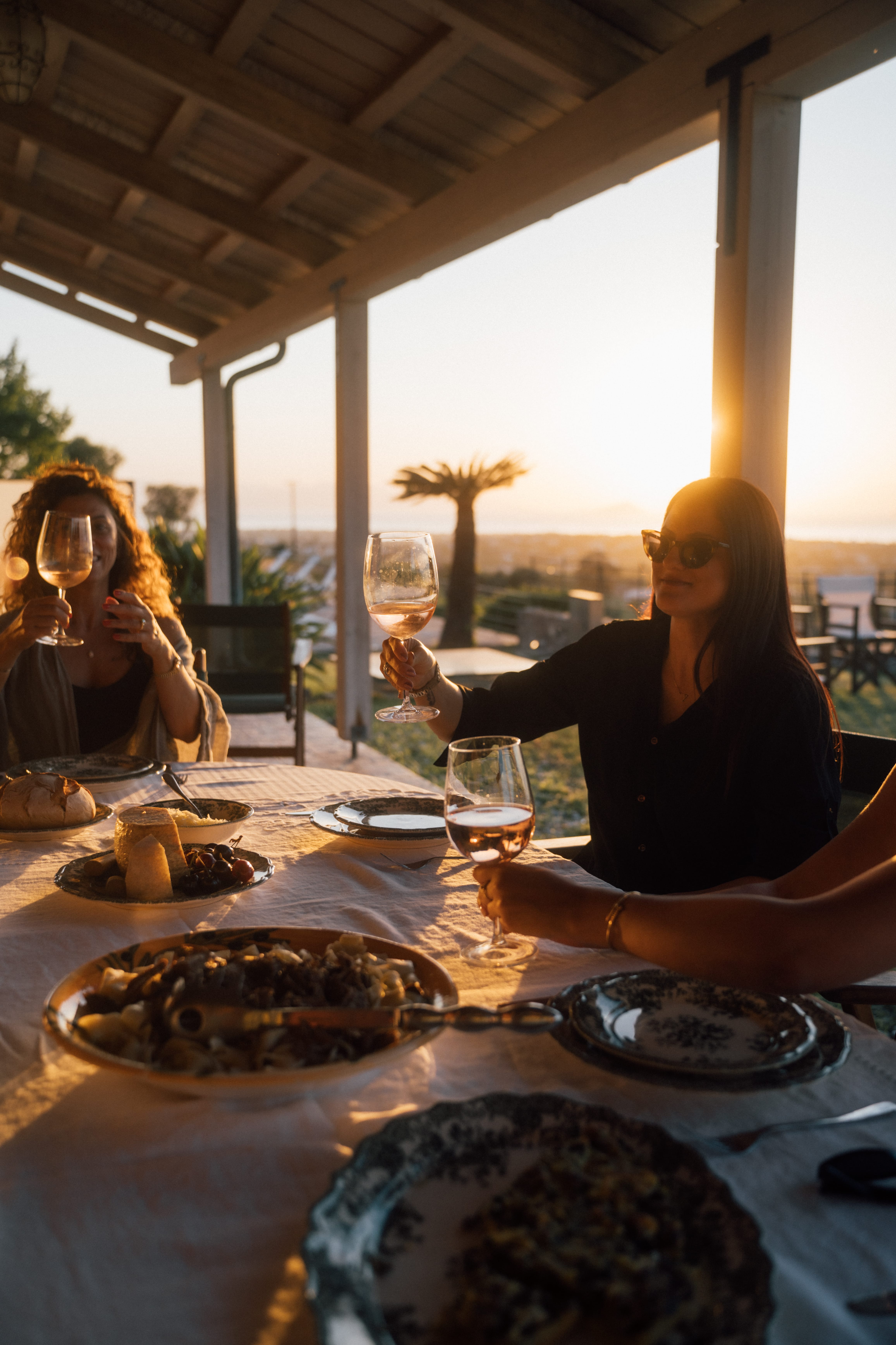 a couple of women sitting at a table with food and drinks