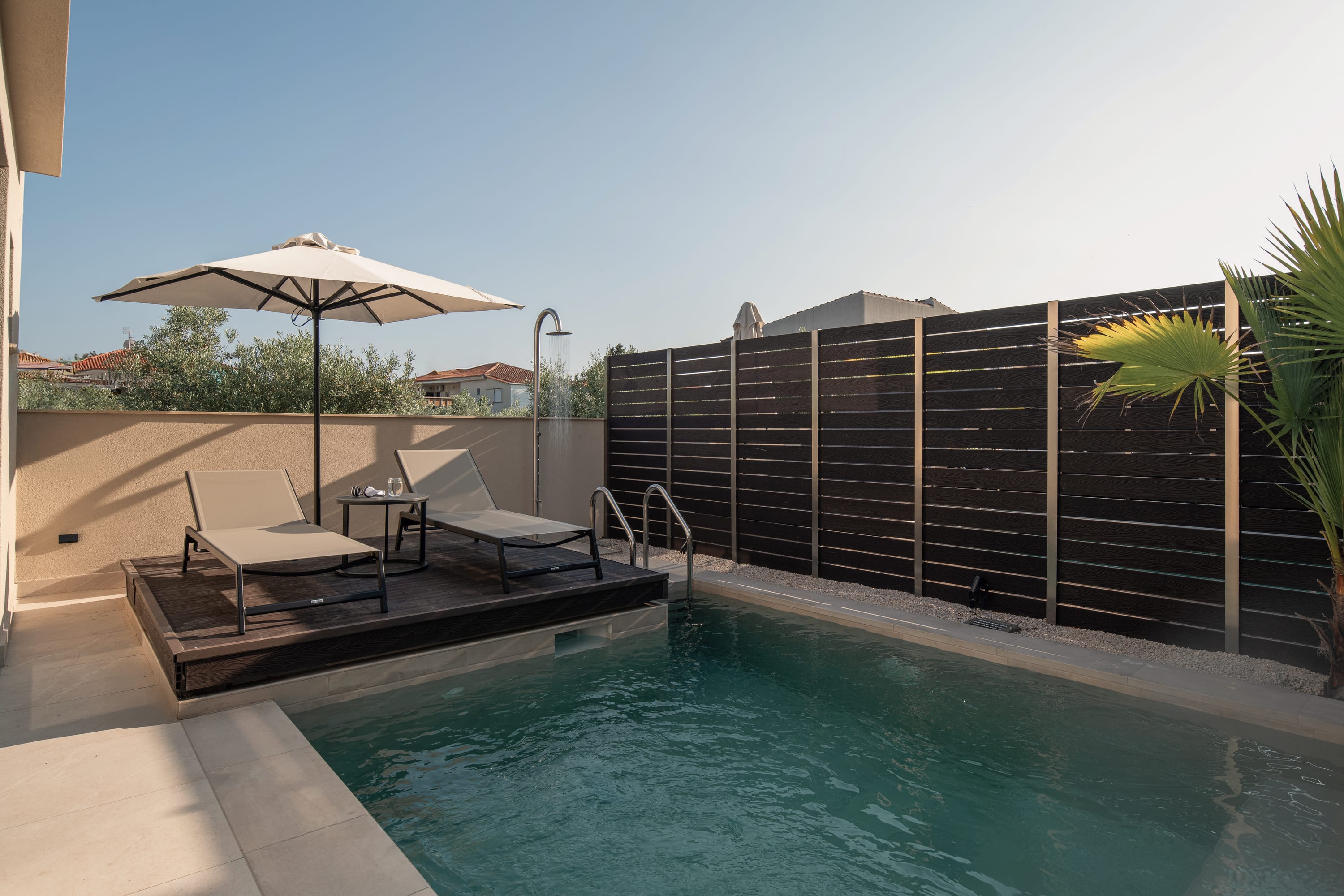 a pool with lounge chairs and umbrellas by a building