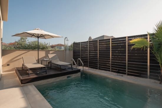 a pool with lounge chairs and umbrellas by a building