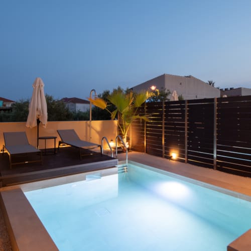 a pool with a deck and chairs by it and a building in the background