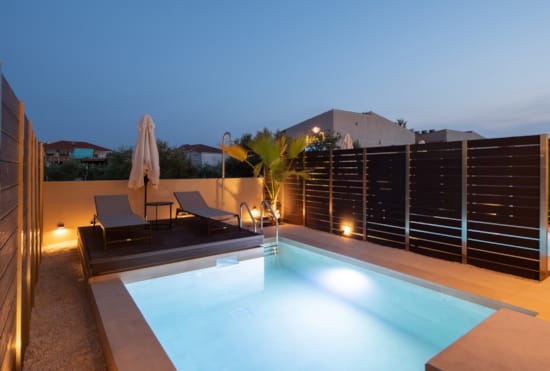 a pool with a deck and chairs by it and a building in the background
