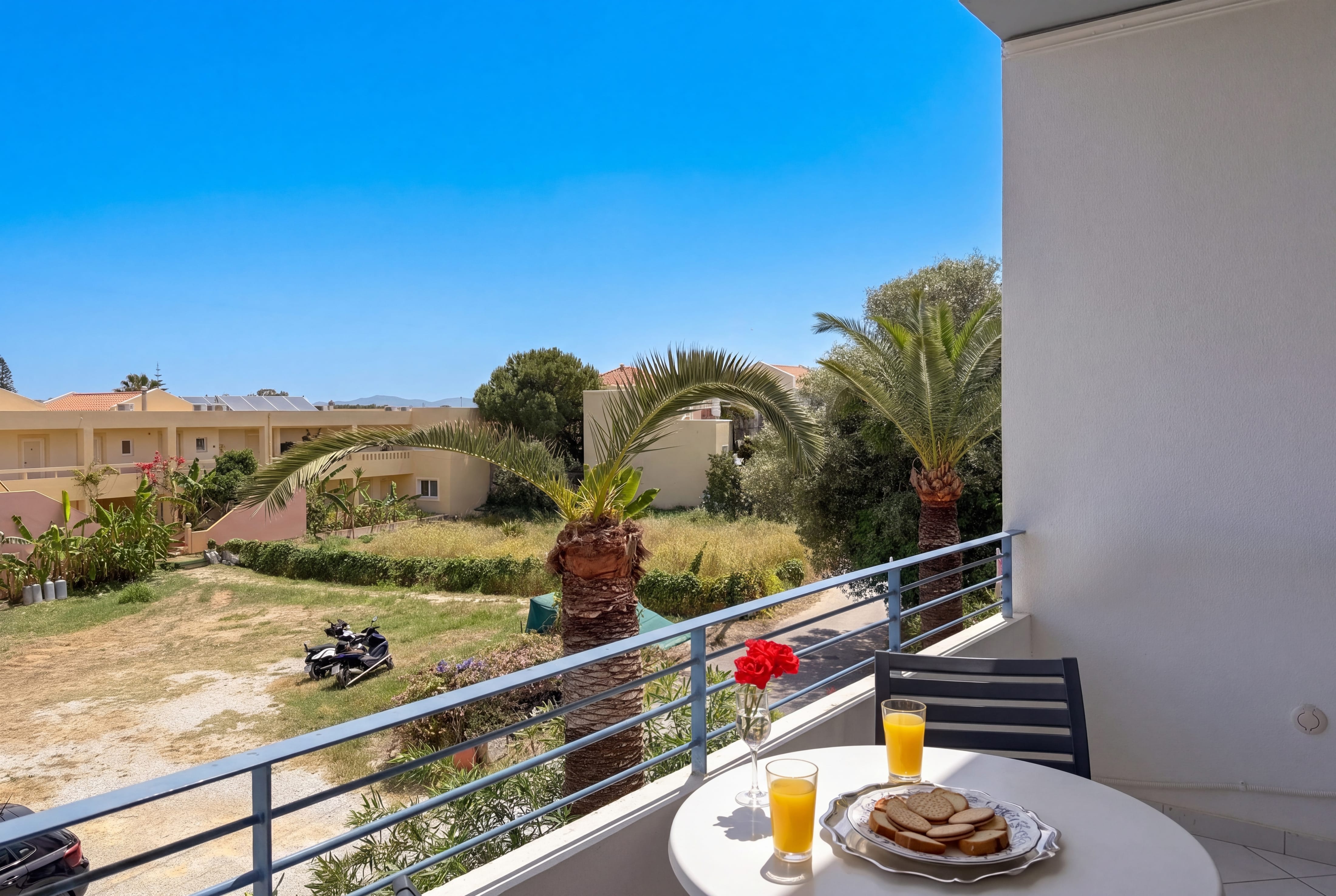 a table with food on it and a chair on a balcony with a view of a dirt road and trees