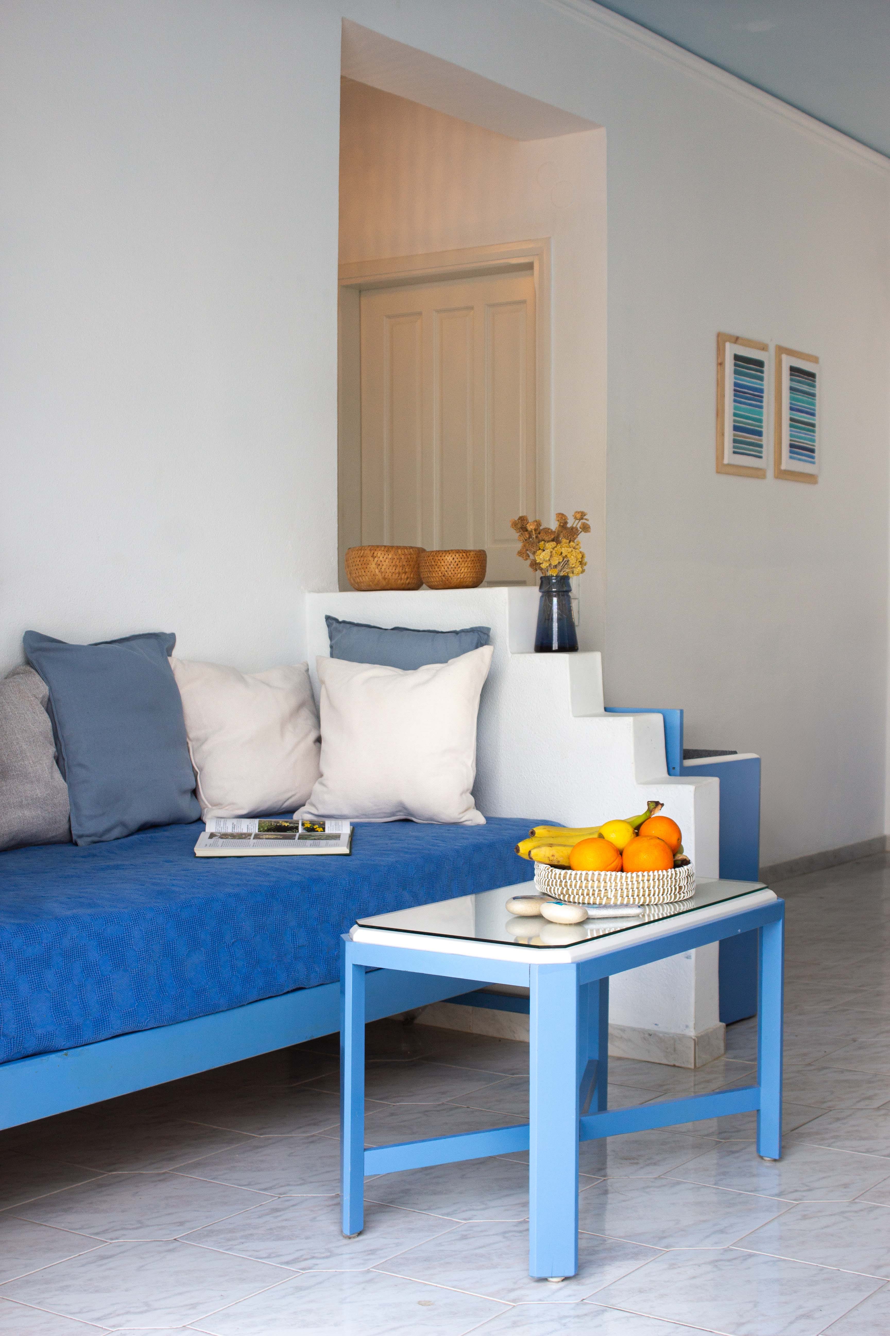 a blue couch with a table and a vase of fruit on it