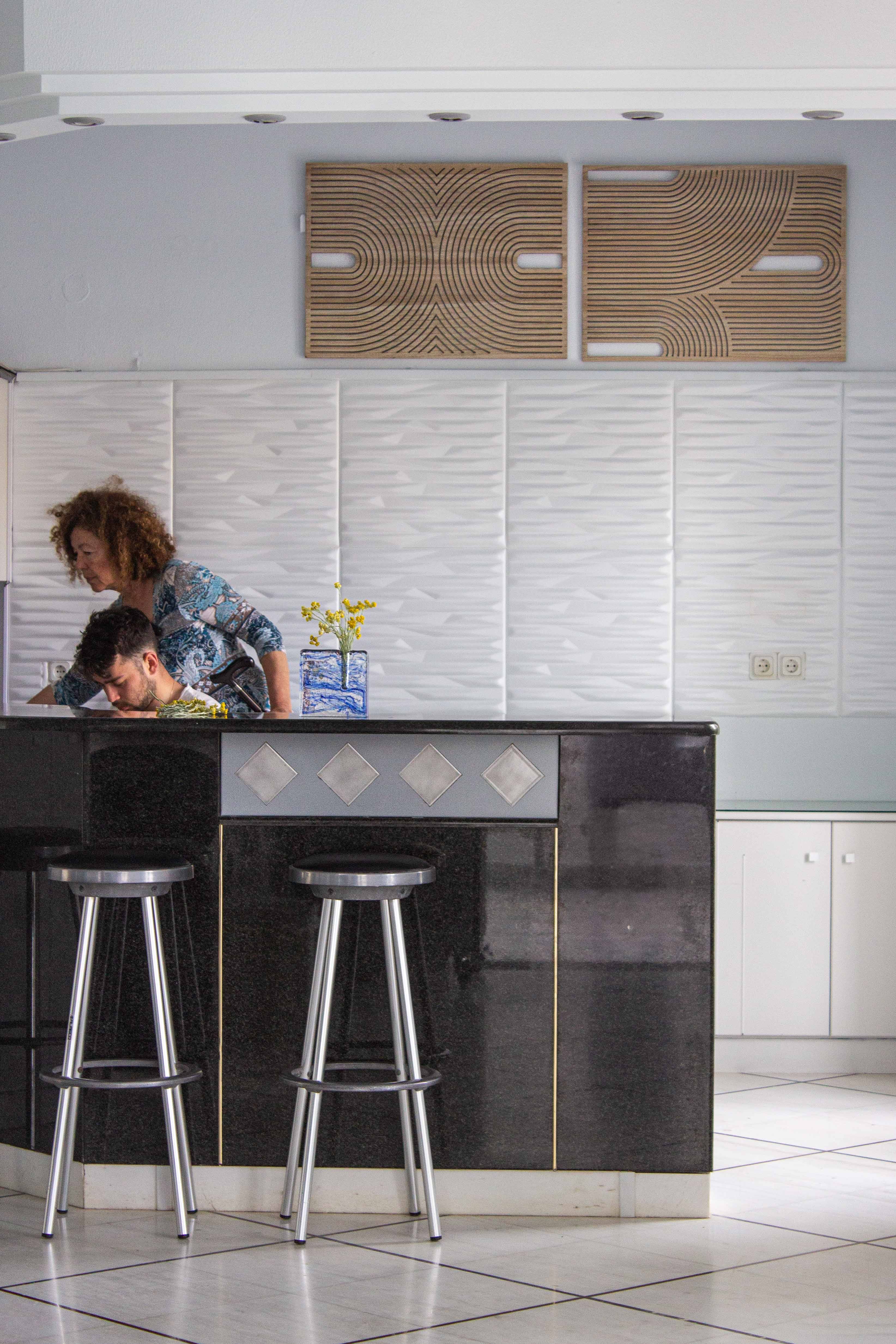 a couple of people sitting at a table in a room with a white wall and a window