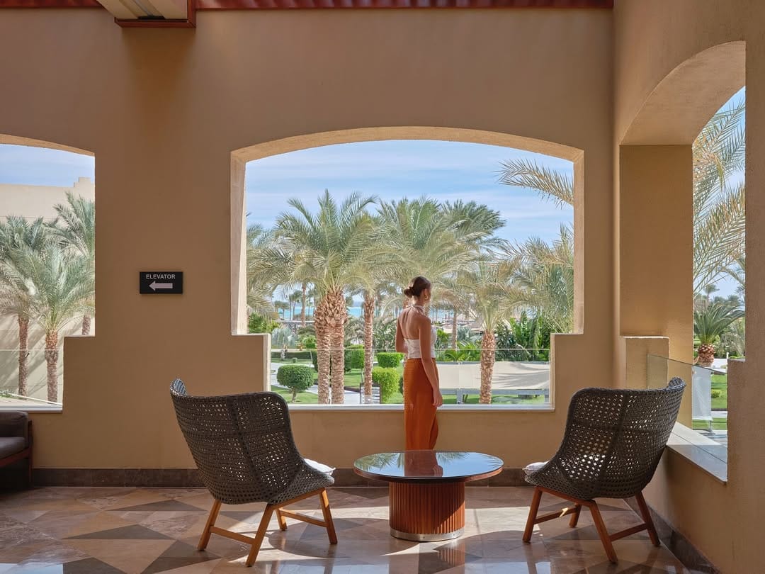 a table with chairs and a statue in the middle of a room with palm trees