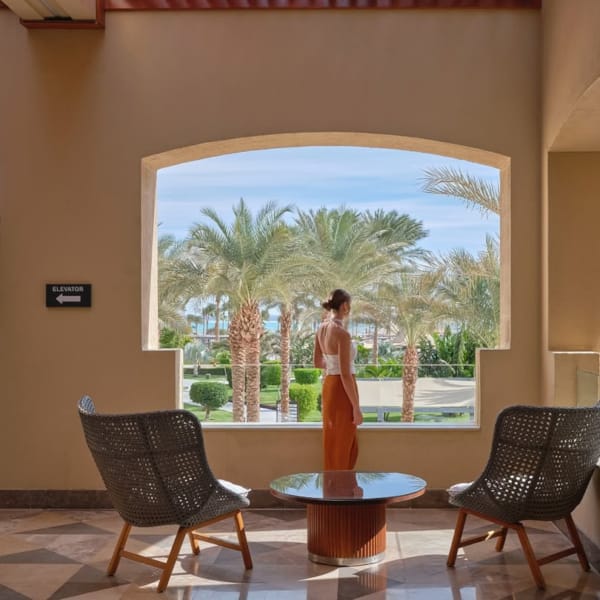 a table with chairs and a statue in the middle of a room with palm trees