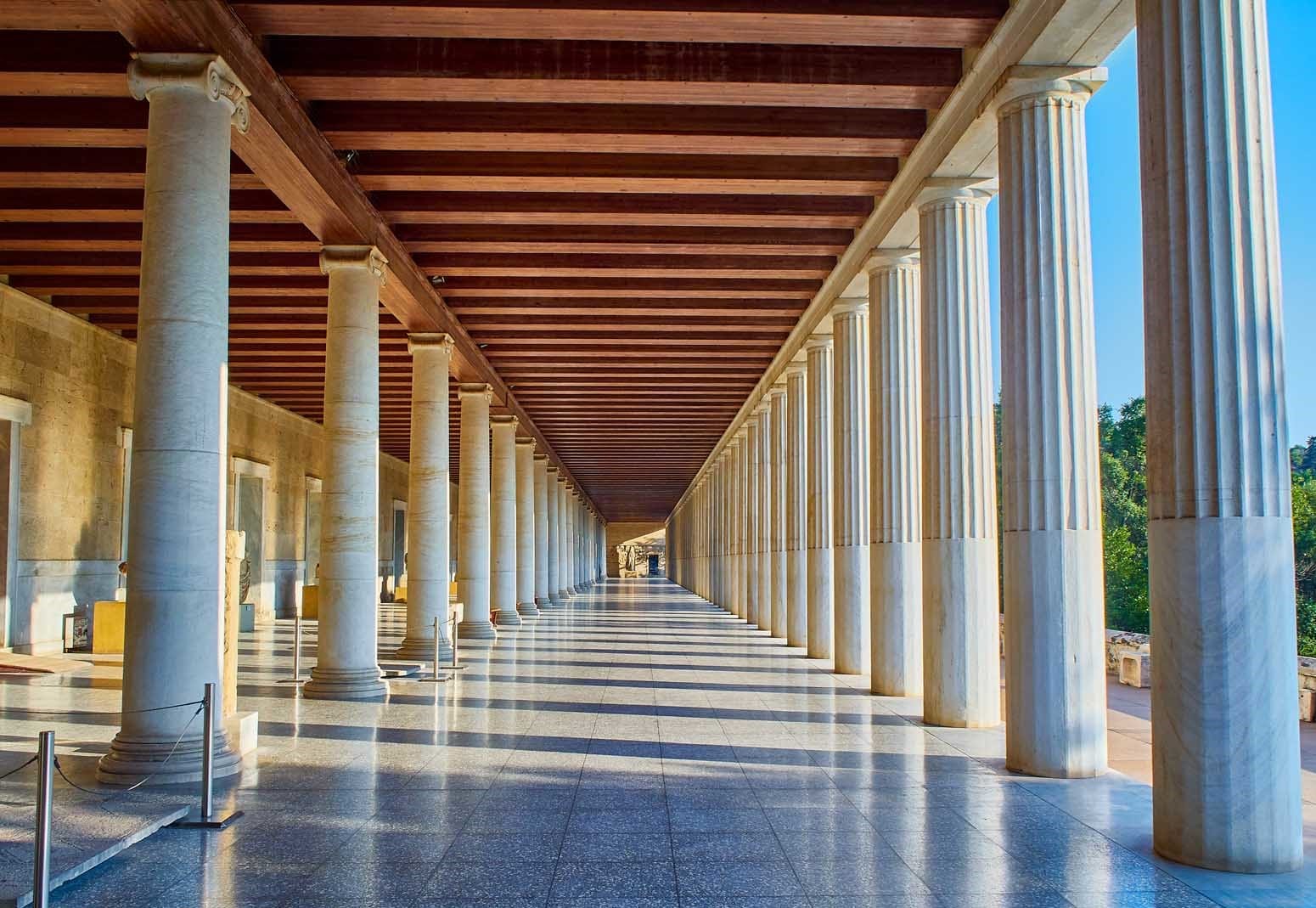 a long hallway with pillars with Stoa of Attalos in the background