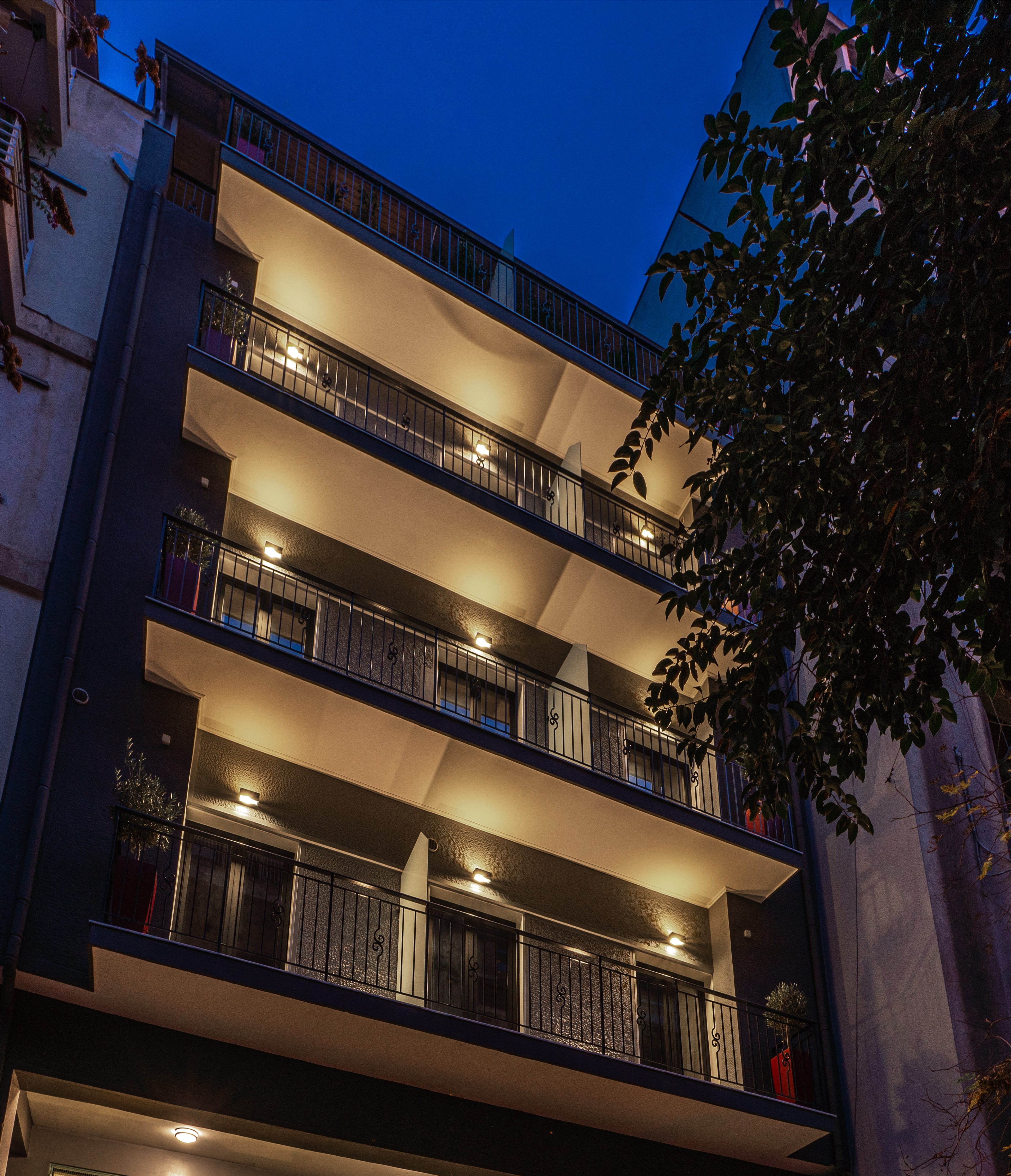 a building with balconies and a tree in front