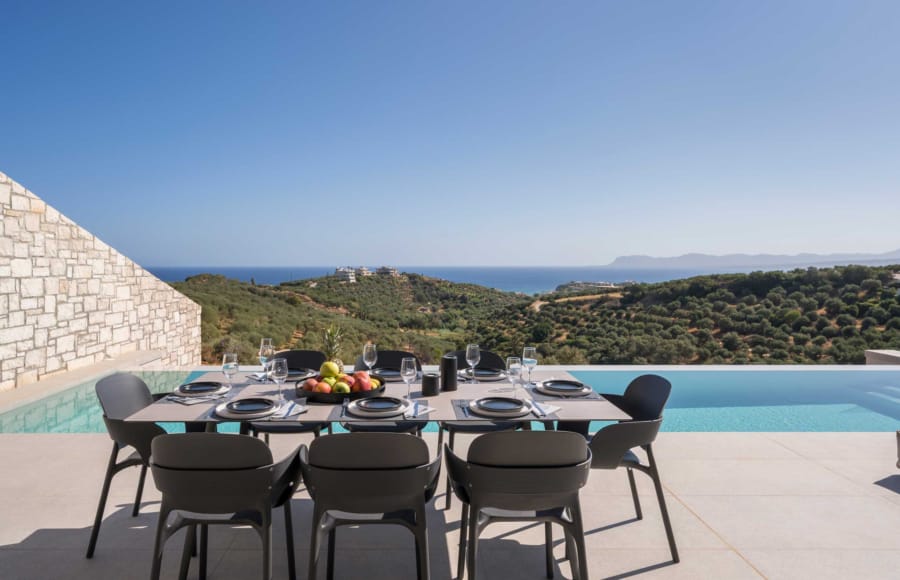 a table with chairs and a pool in the background