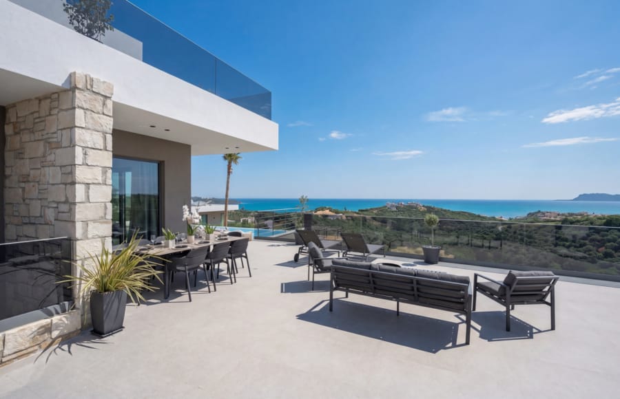 a patio with chairs and a balcony overlooking the ocean