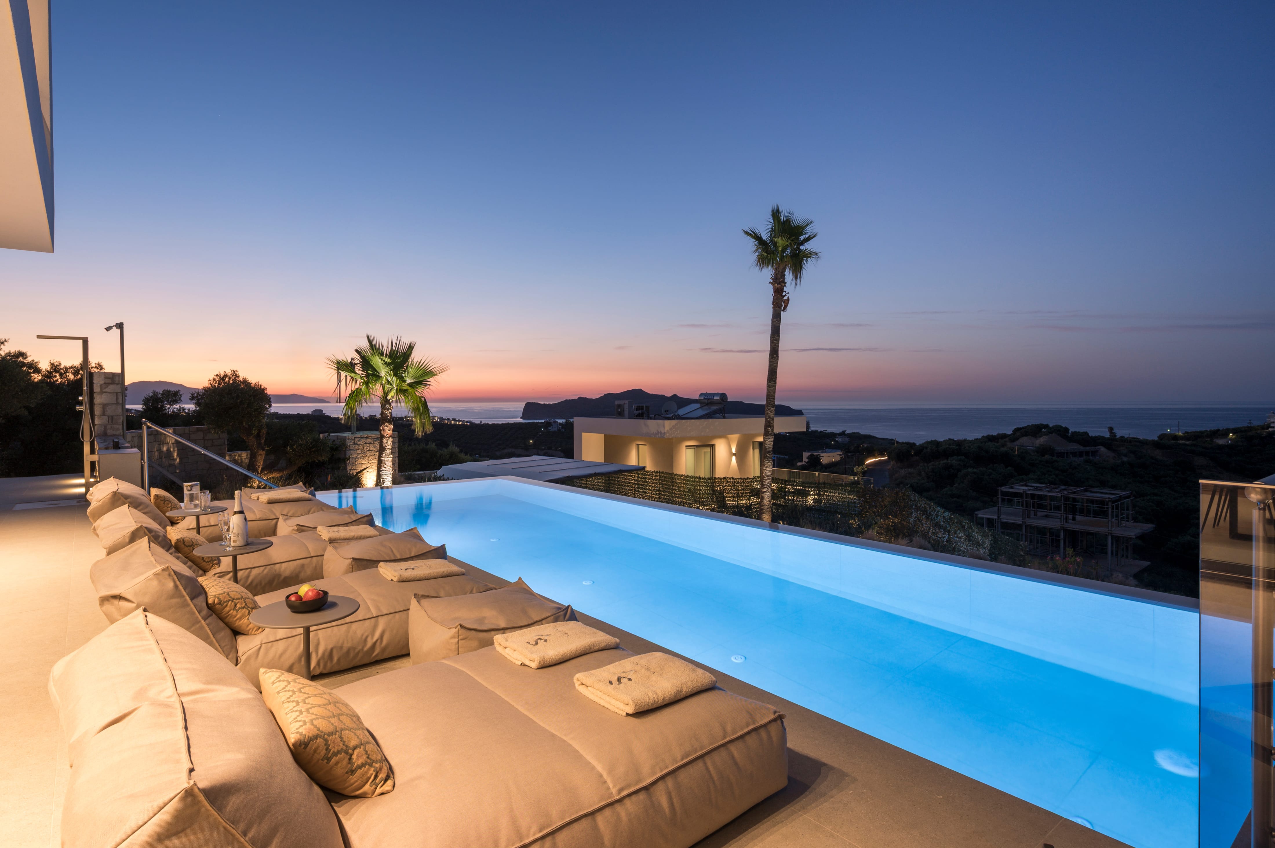 a pool with a couch and a table with a sunset in the background