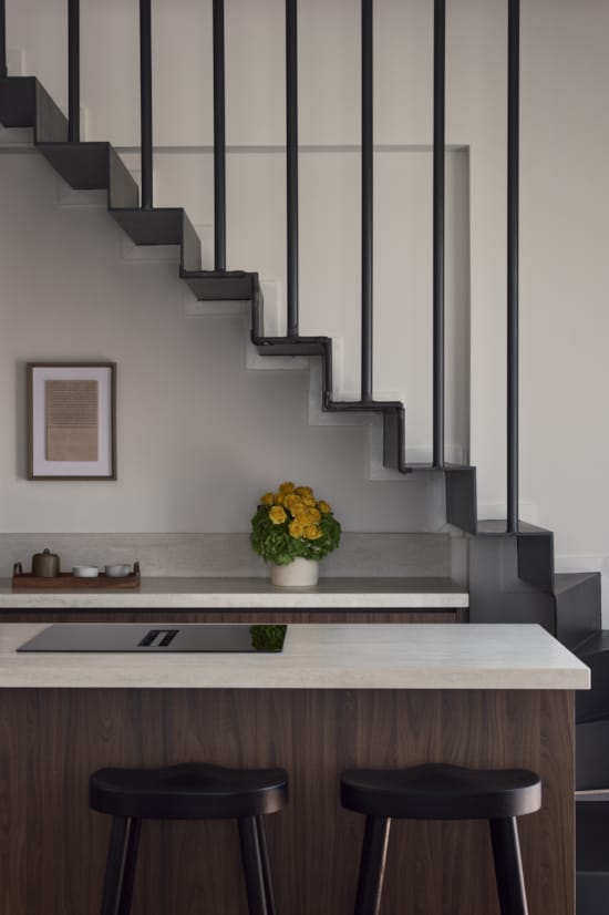 a room with a staircase and a plant on a counter