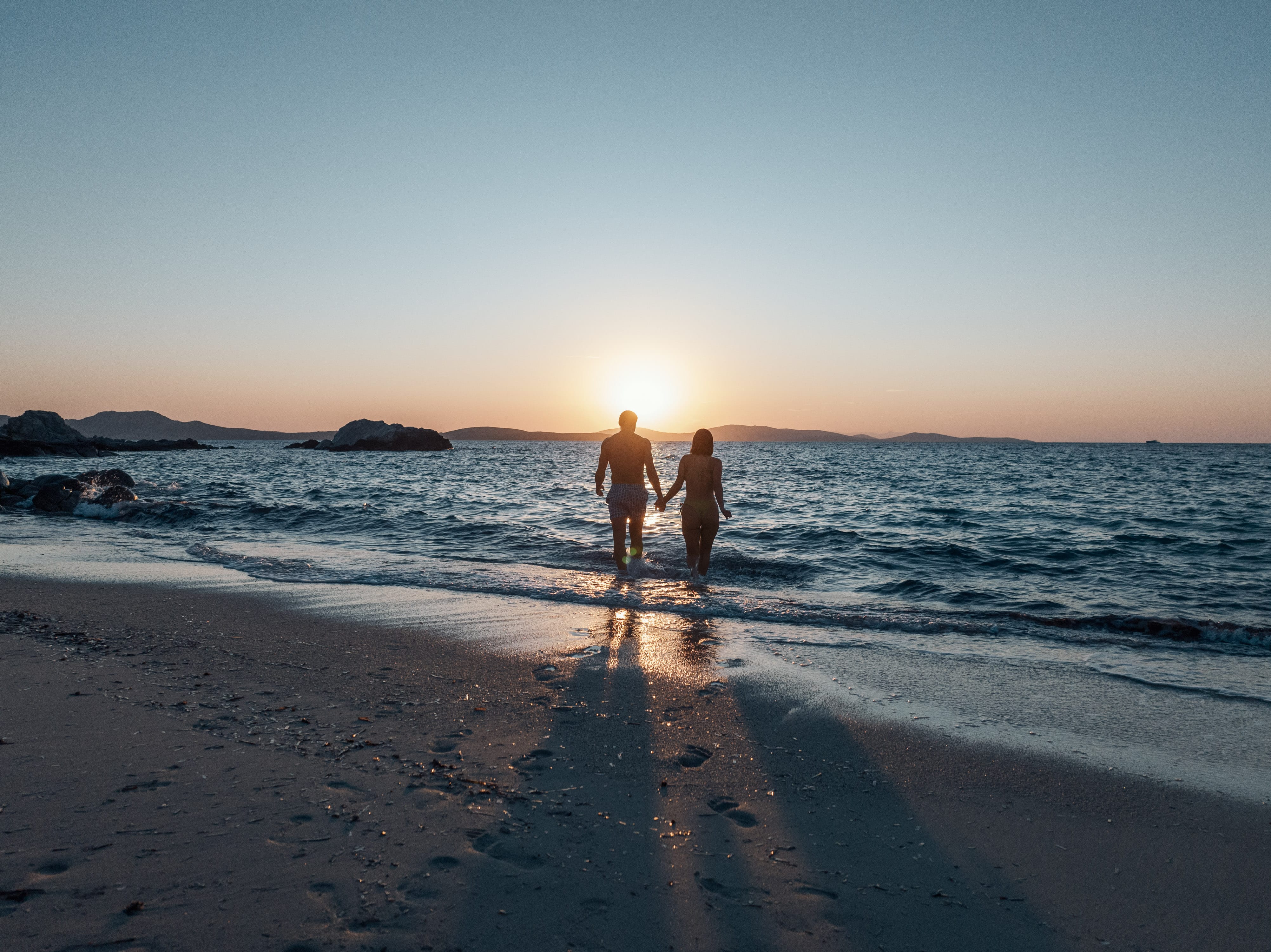 a couple of people walking on a beach