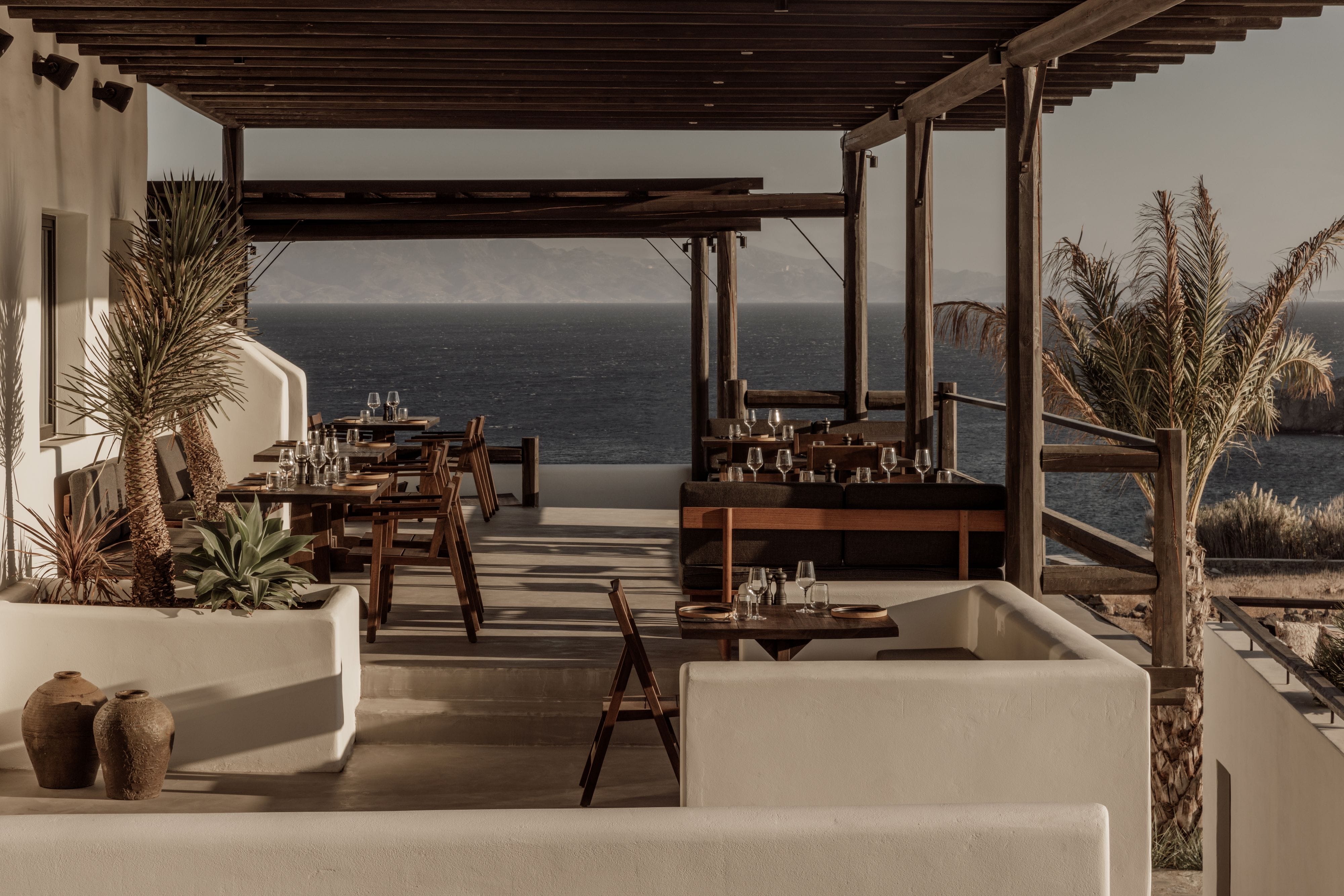 a room with a table and chairs and a body of water in the background