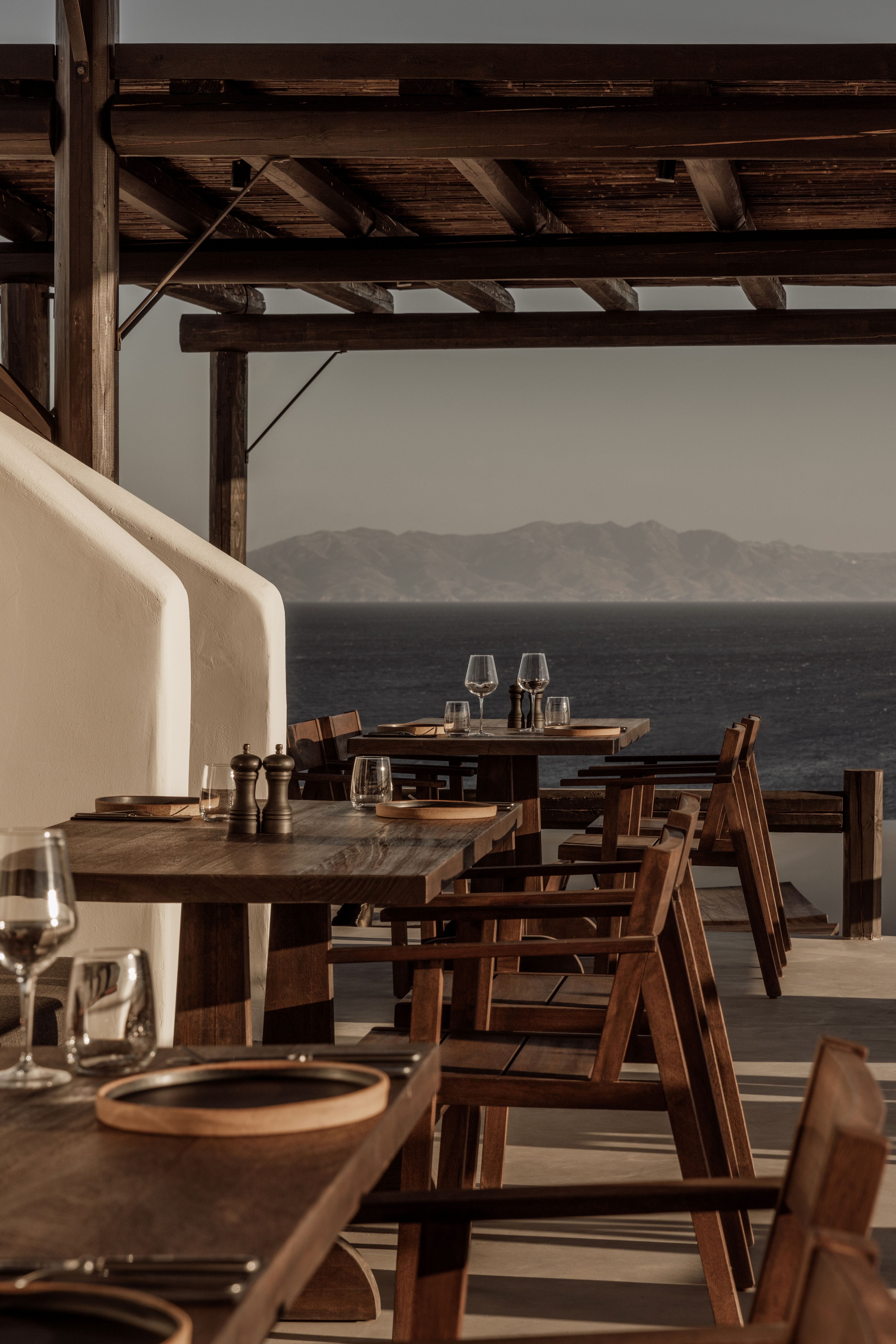 a table with glasses and plates on it by a body of water