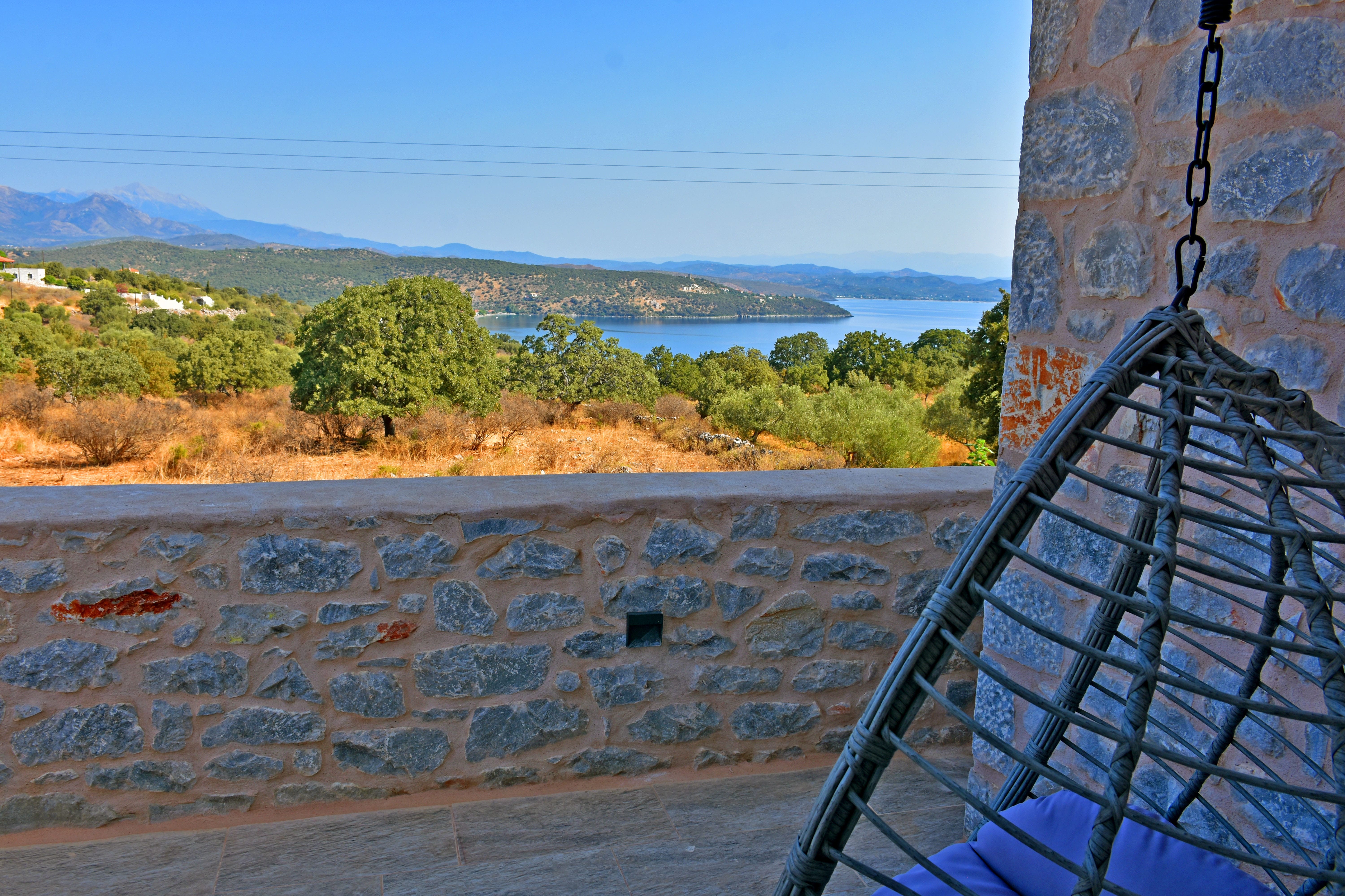 a stone wall with a railing and trees and a body of water in the background