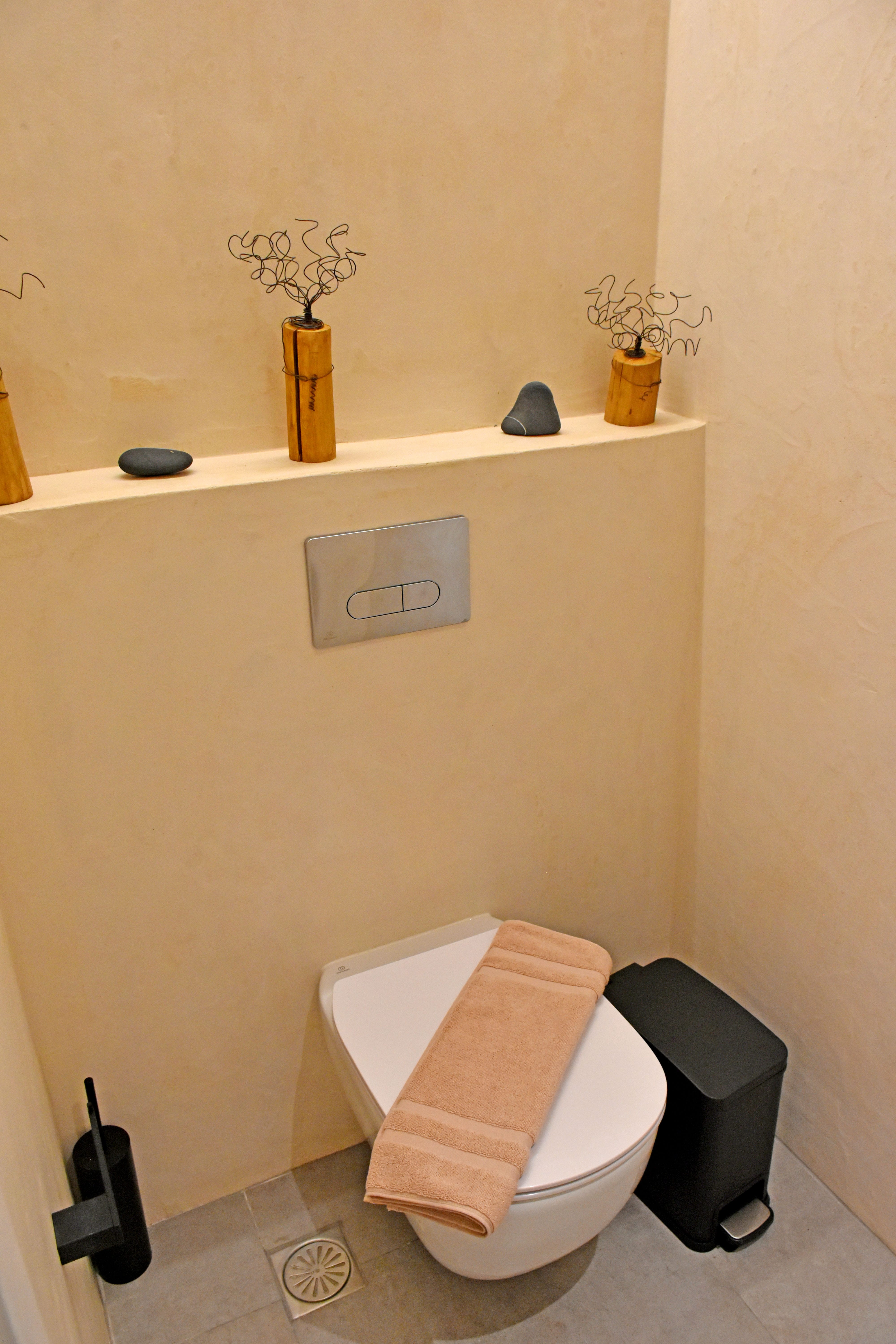 a toilet with a shelf above it