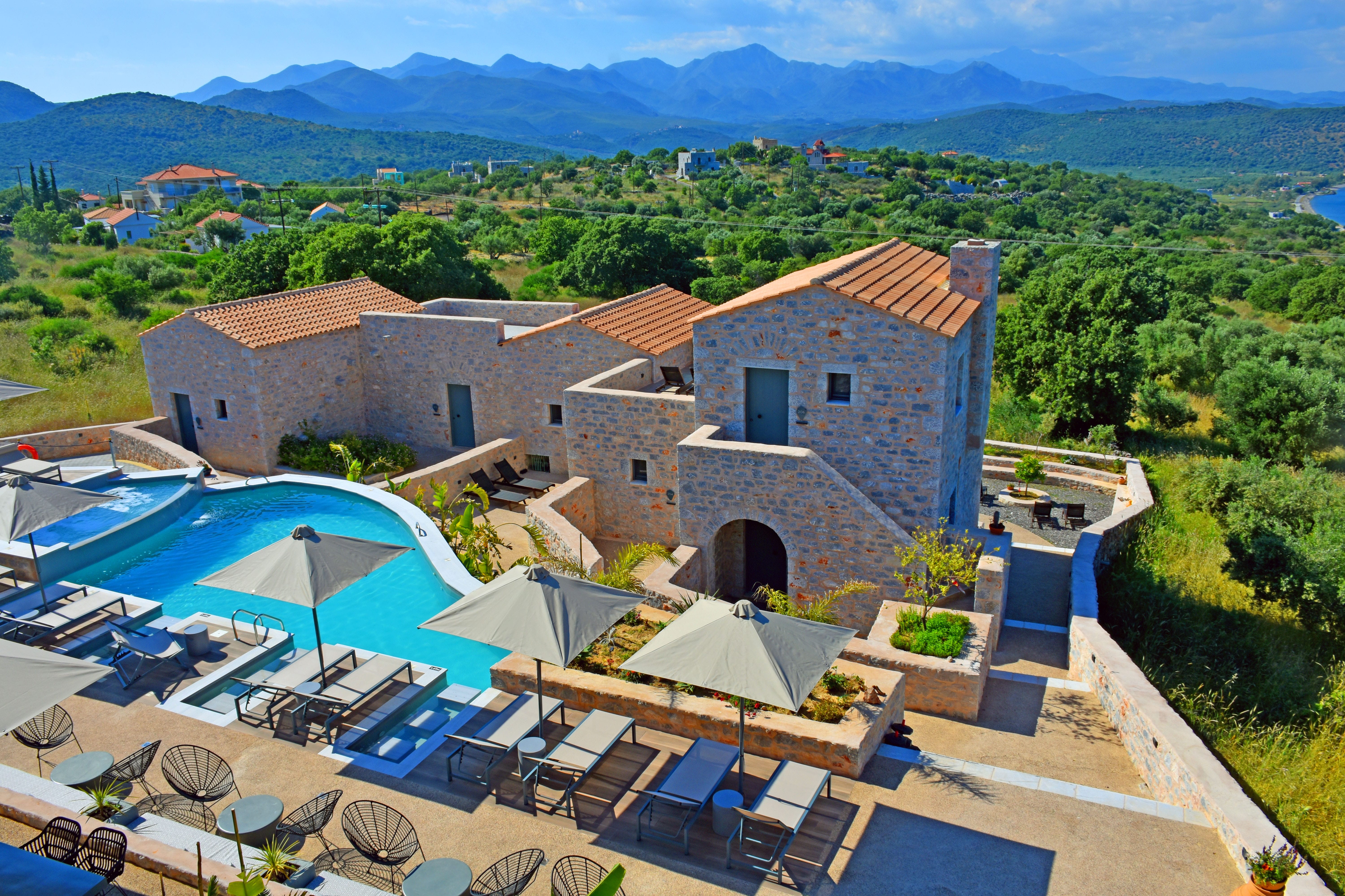 a house with a pool and a large yard with trees and mountains in the background