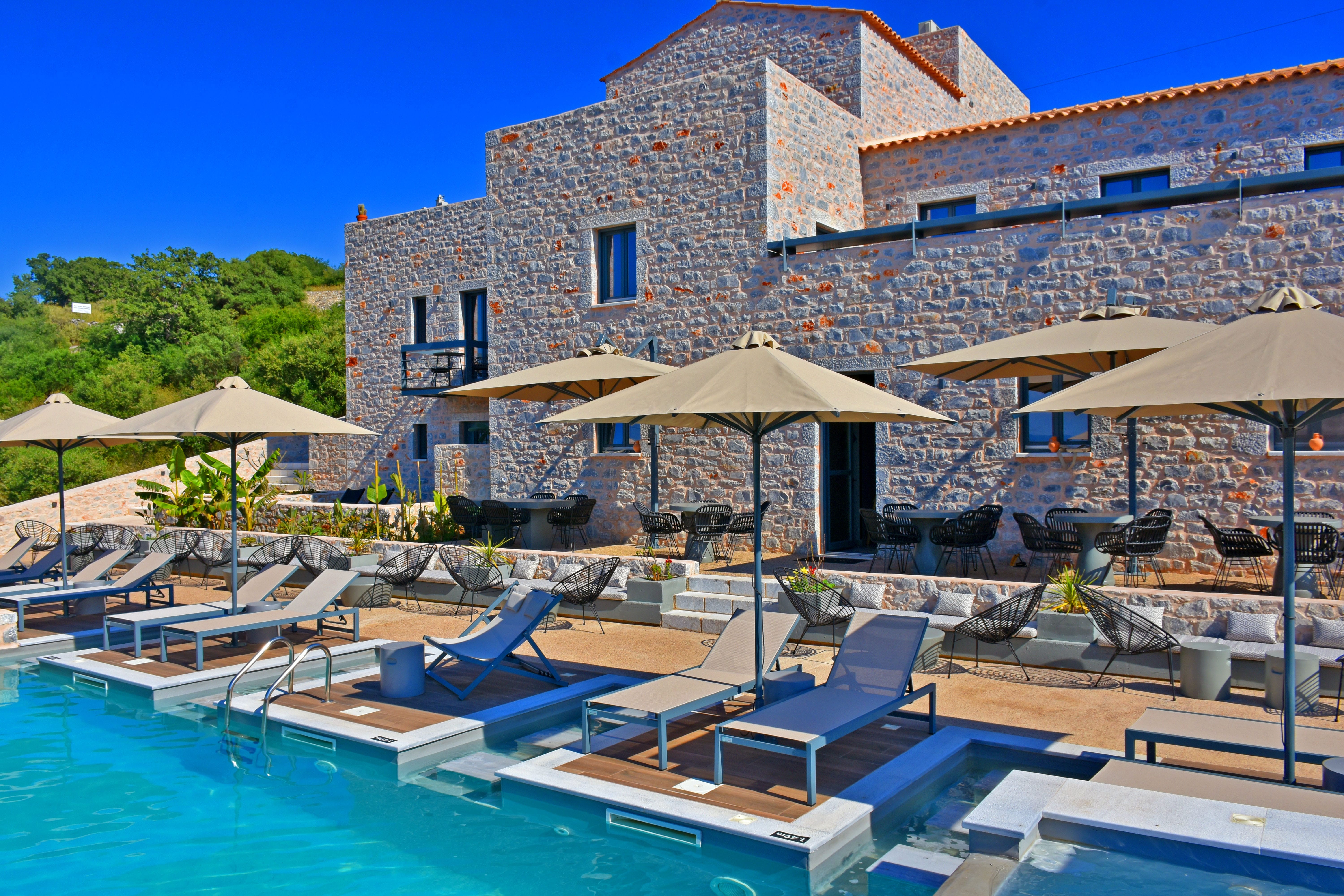 a pool with lounge chairs and umbrellas next to a building