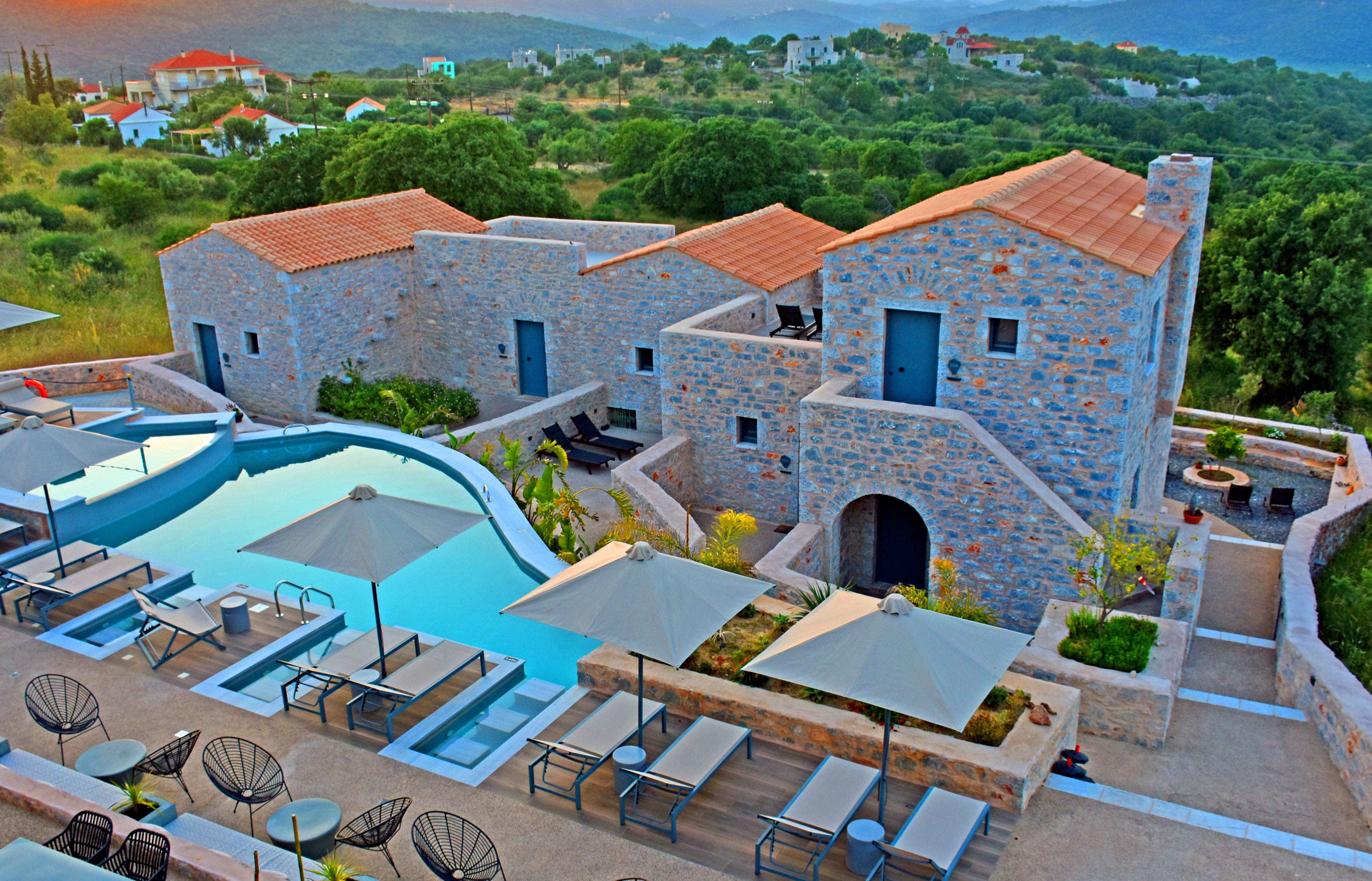 a building with a pool and a patio with chairs and umbrellas