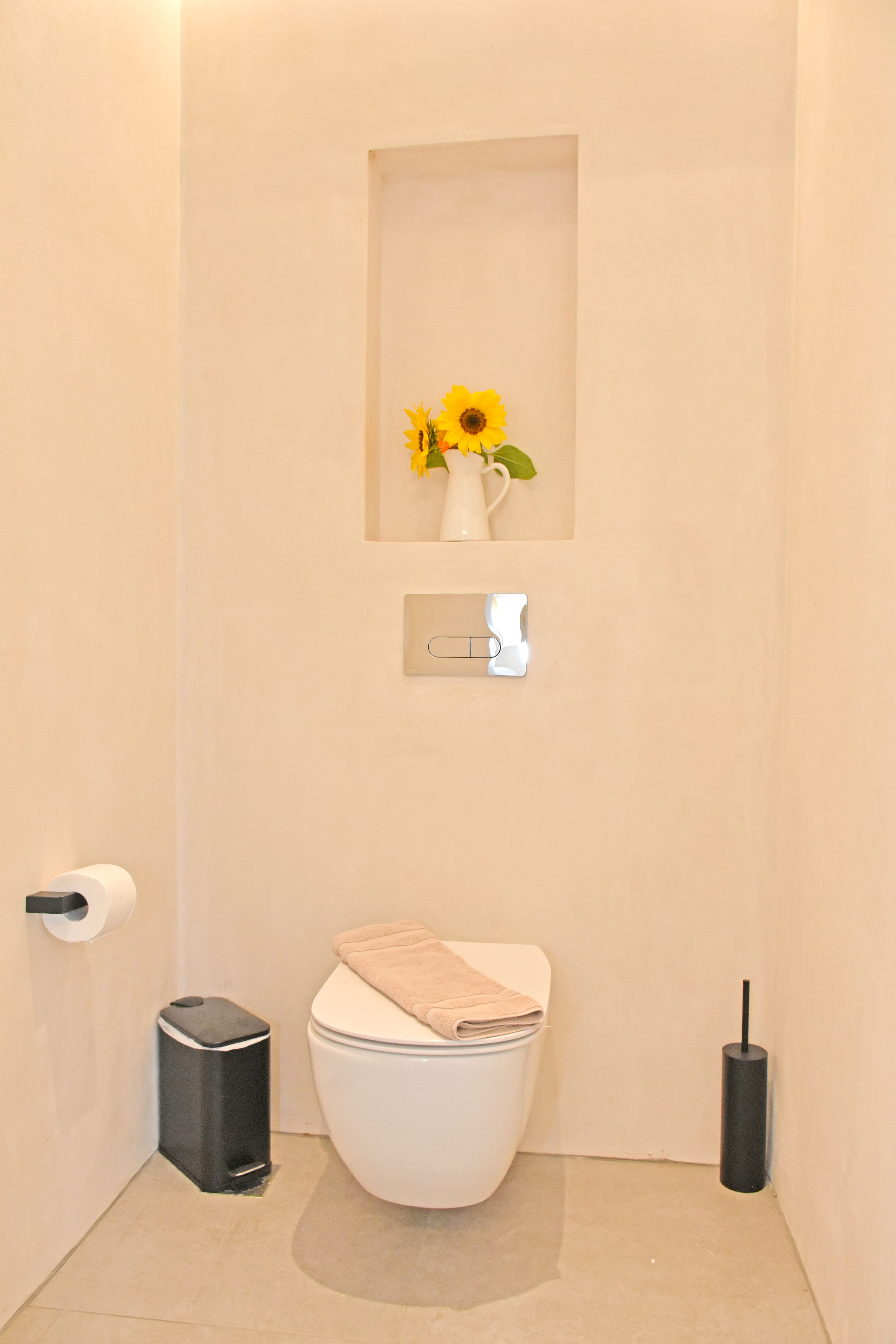 a toilet with a flower vase on the wall