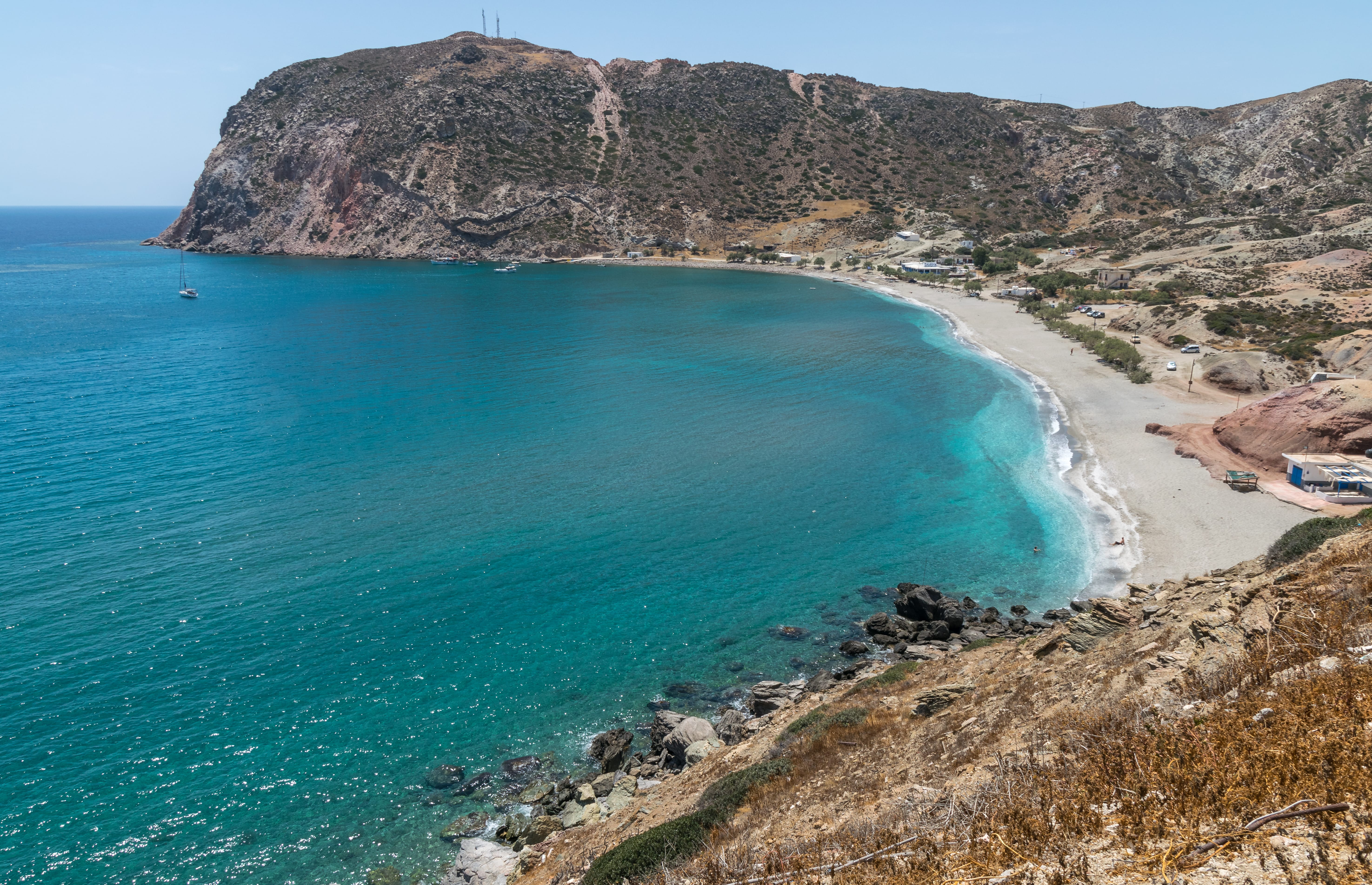 a beach with a large rock cliff