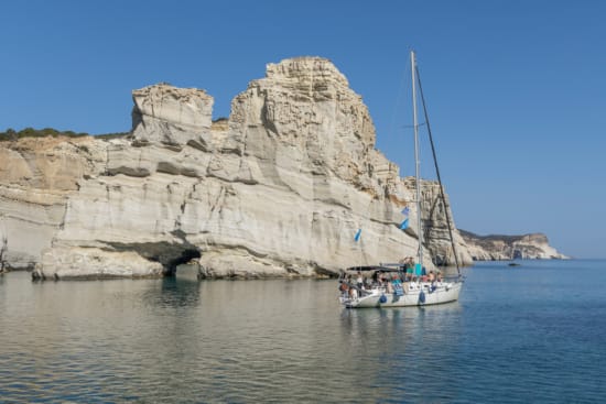 a boat in the water by a large rock formation