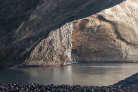 a body of water with a rocky cliff in the background