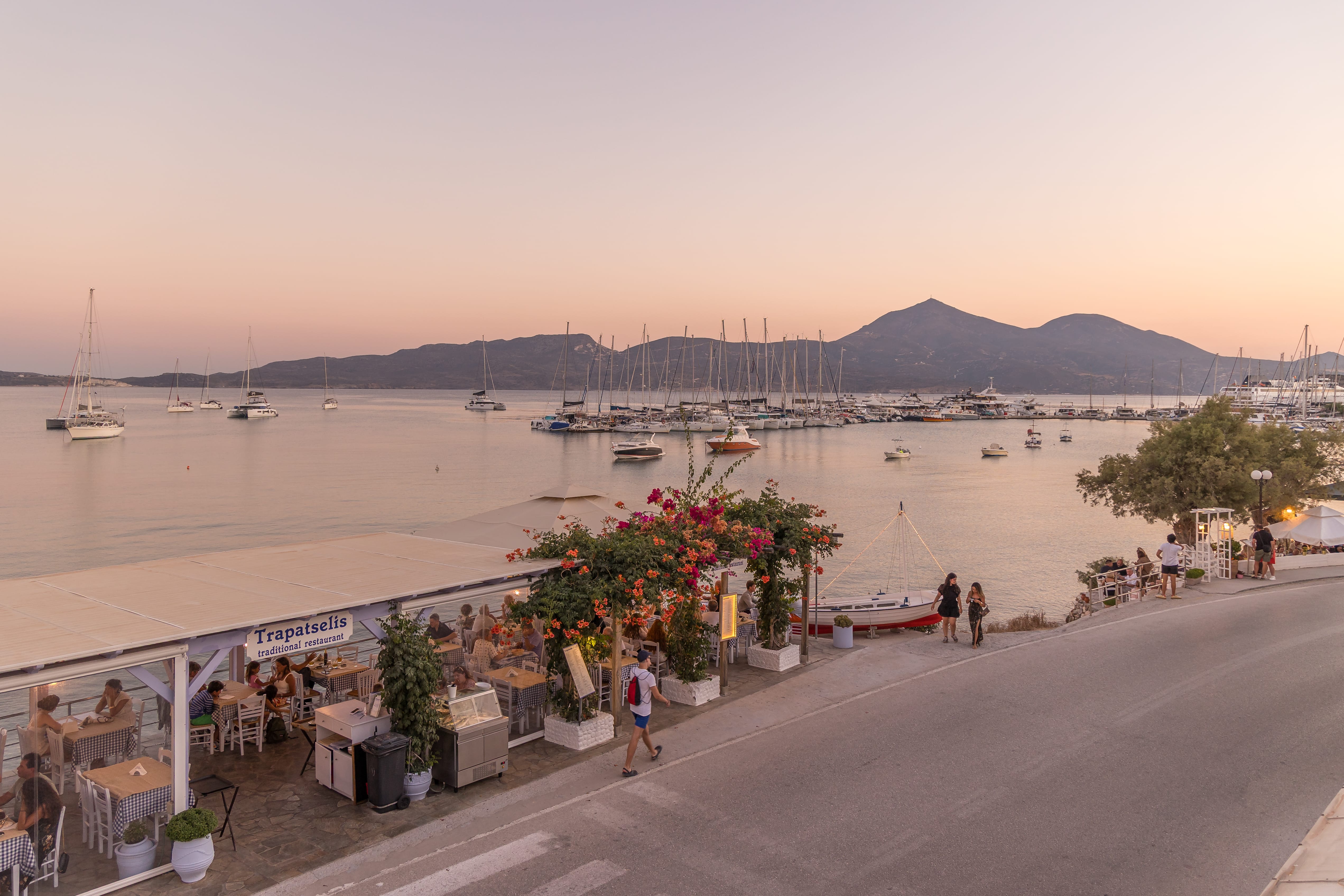 a road with a body of water and people walking on it