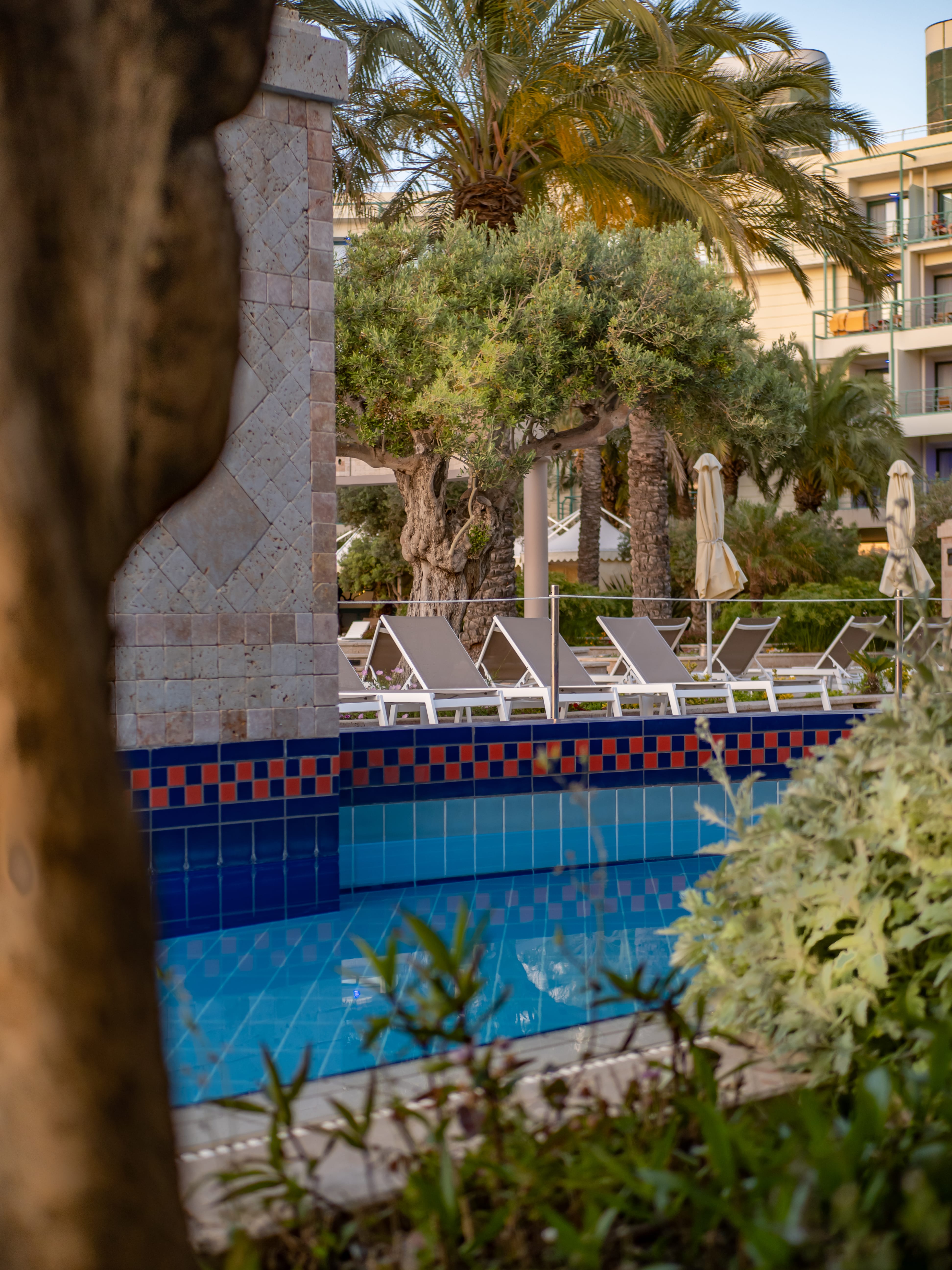 a swimming pool with chairs and umbrellas next to a building